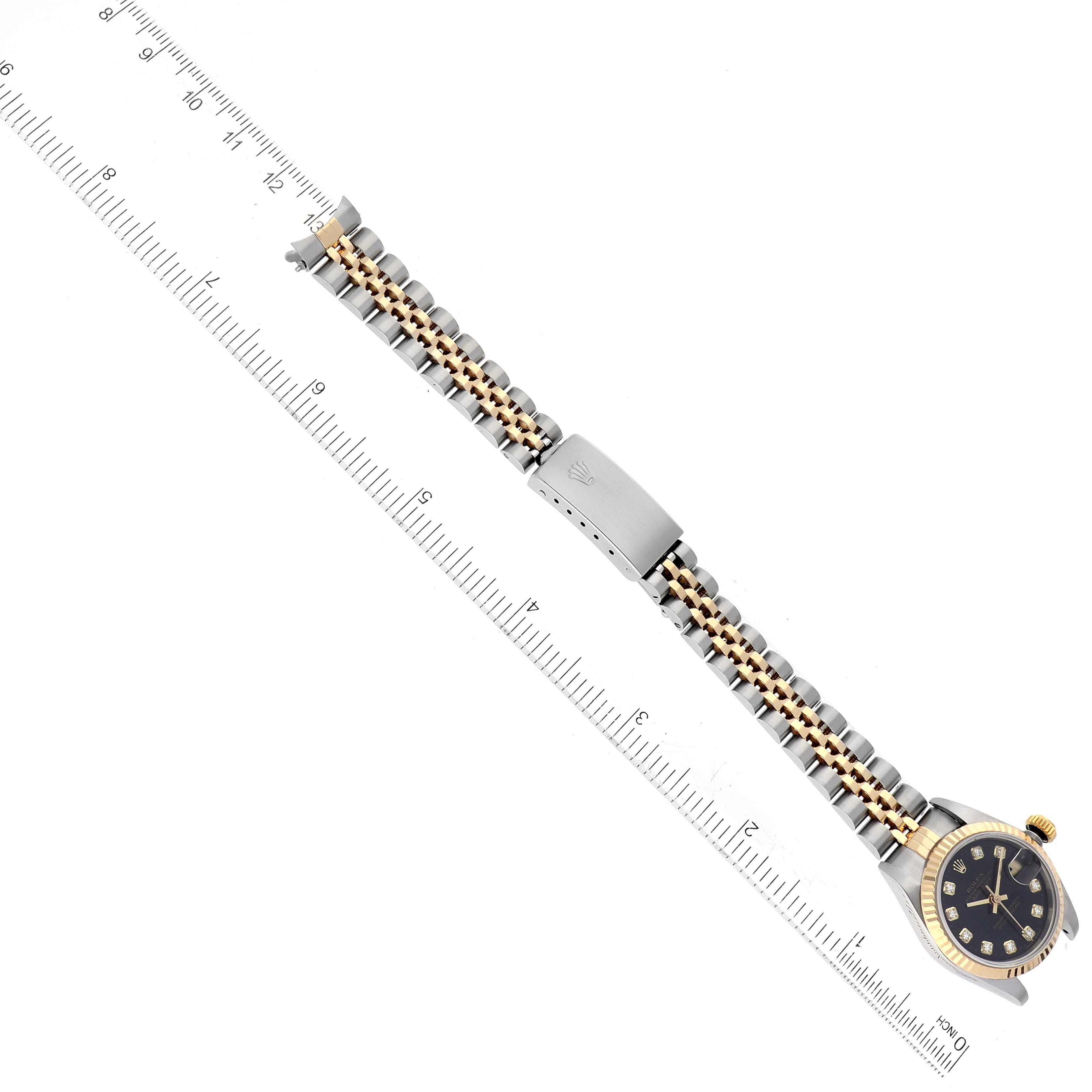 The image shows an overhead view of a Rolex Datejust 69173G Women's Steel and Gold (two tone) Black Dial 69173G Women's Steel and Gold (two tone) Black Dial watch with its entire band and part of a measuring ruler.