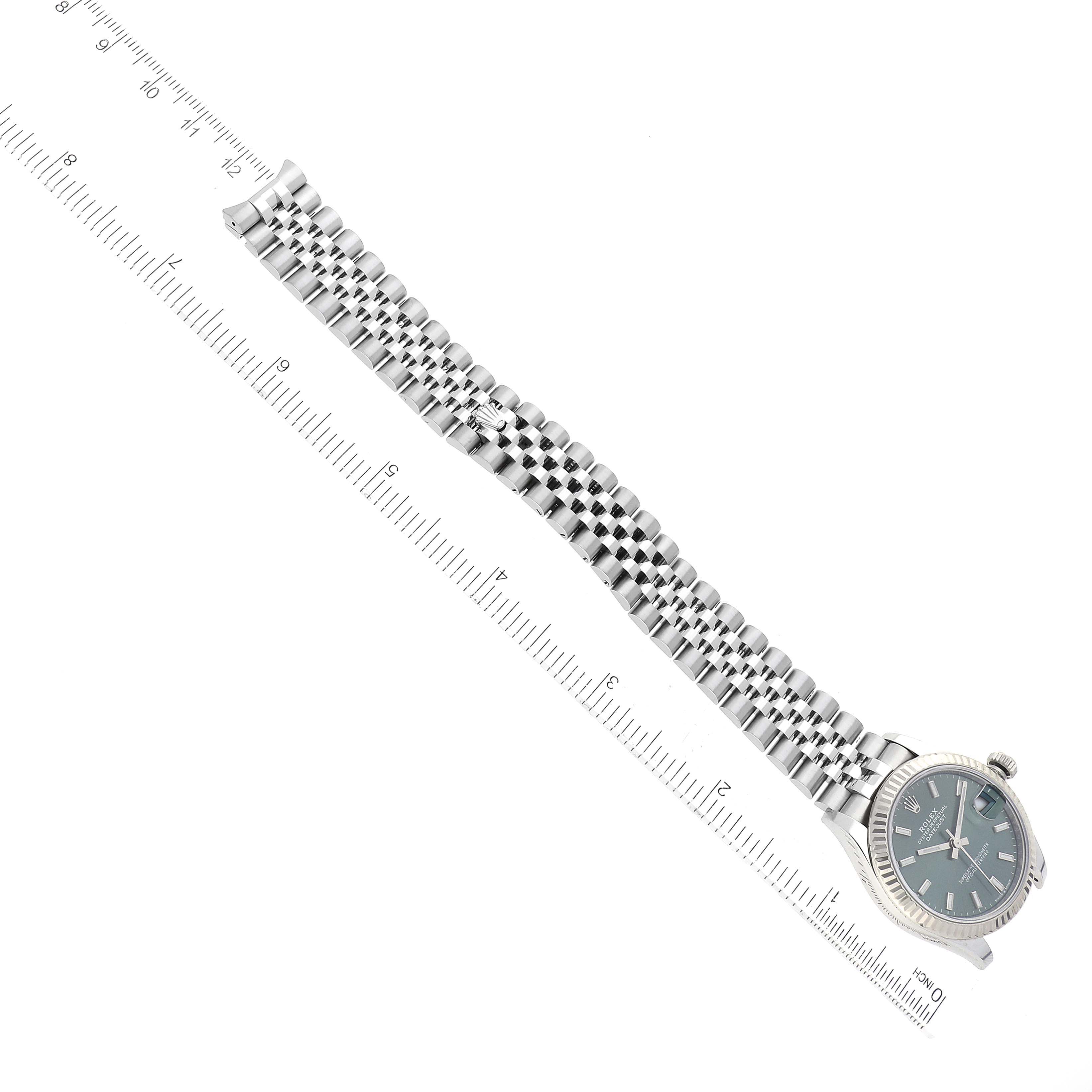 The image shows a top view of a Rolex Mid-Size 278274 Women's Stainless Steel Green Dial 278274 Women's Stainless Steel Green Dial watch displaying its face and metal bracelet alongside a ruler.