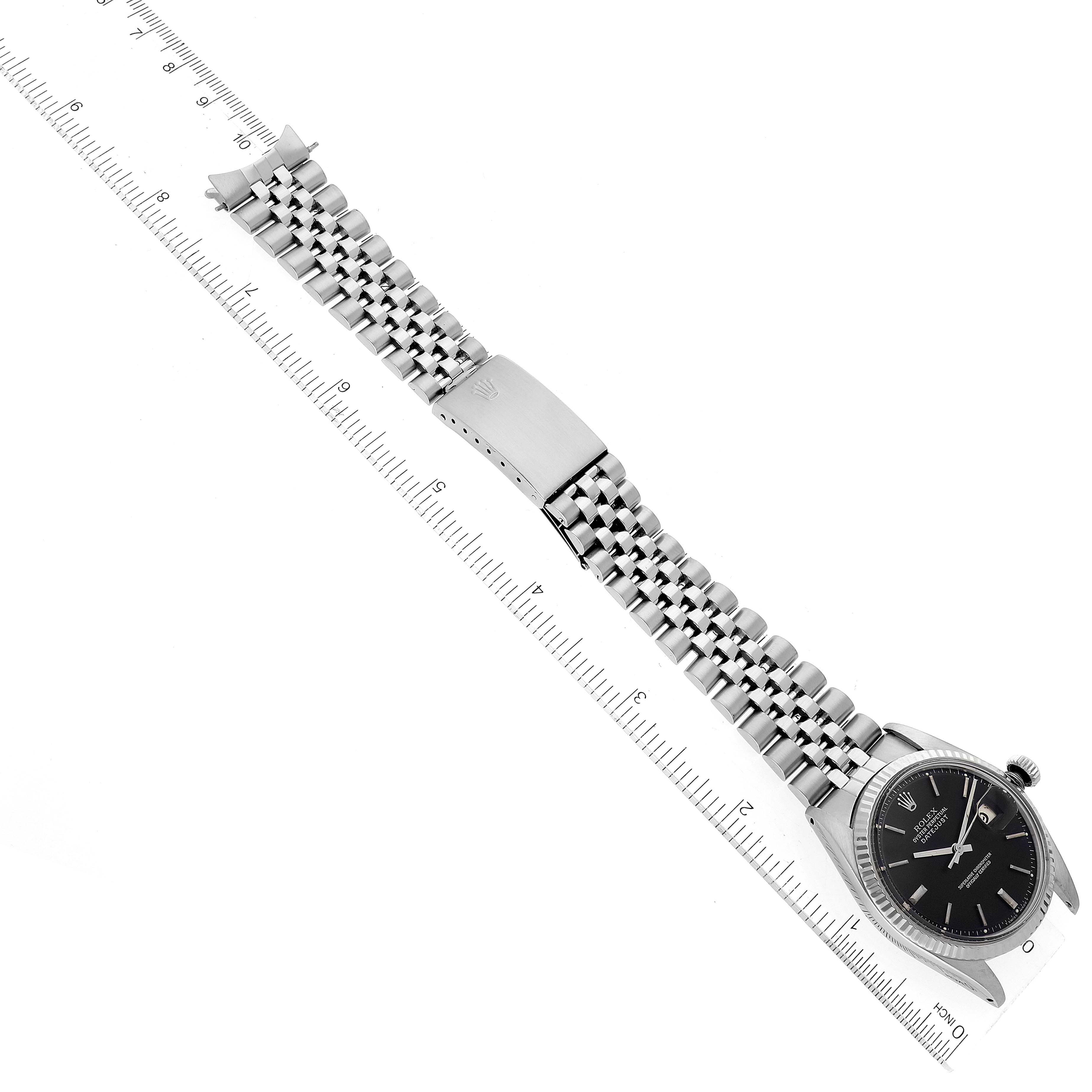 The image shows a top view of the Rolex Vintage Collection 1601 Men's Stainless Steel Black Dial 1601 Men's Stainless Steel Black Dial watch laid flat with its bracelet and clasp visible, alongside a ruler for scale.