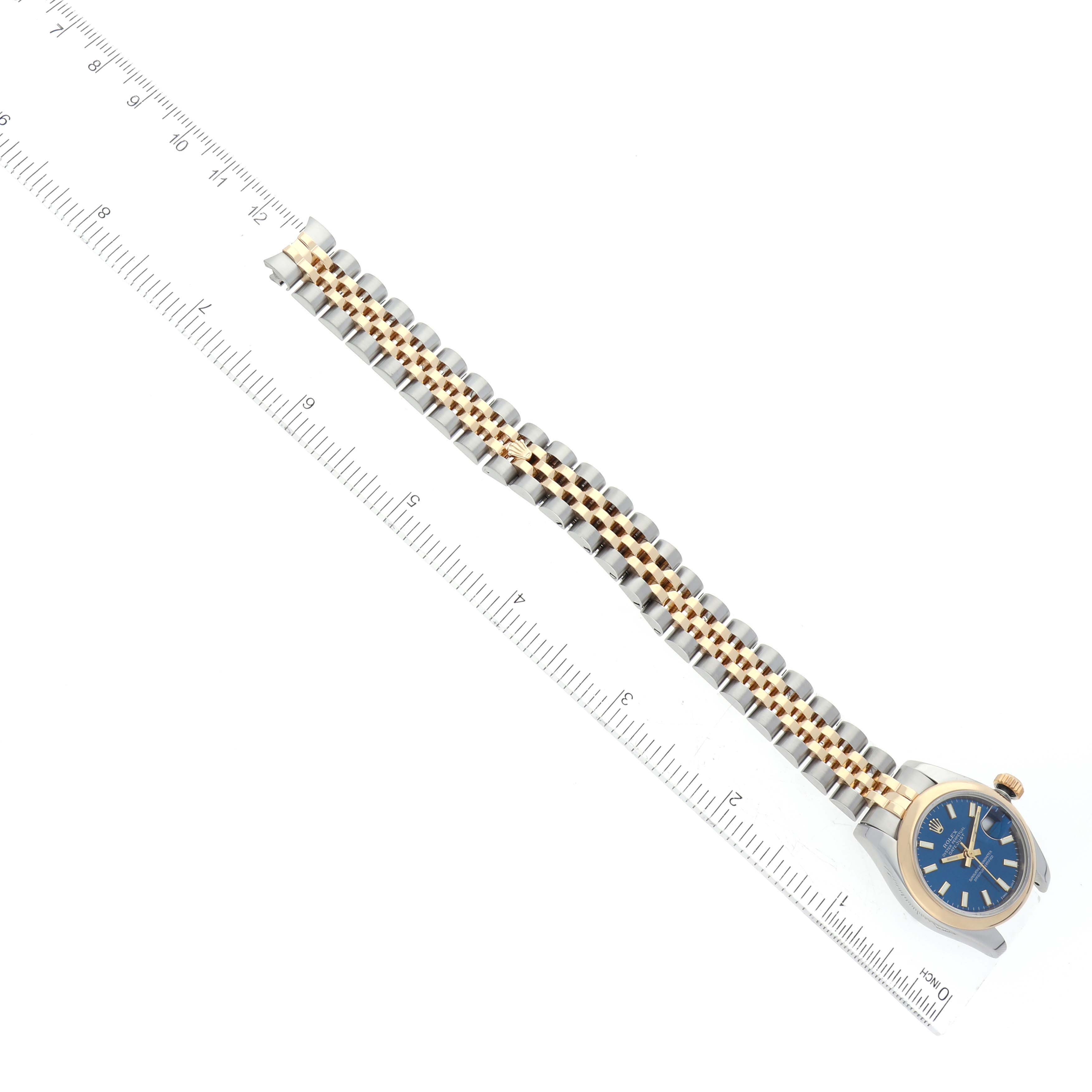 This image shows a Rolex Datejust 179163 Women's Steel and Gold (two tone) Blue Dial 179163 Women's Steel and Gold (two tone) Blue Dial watch laid flat, showcasing its blue dial and two-tone bracelet, with a ruler for scale.