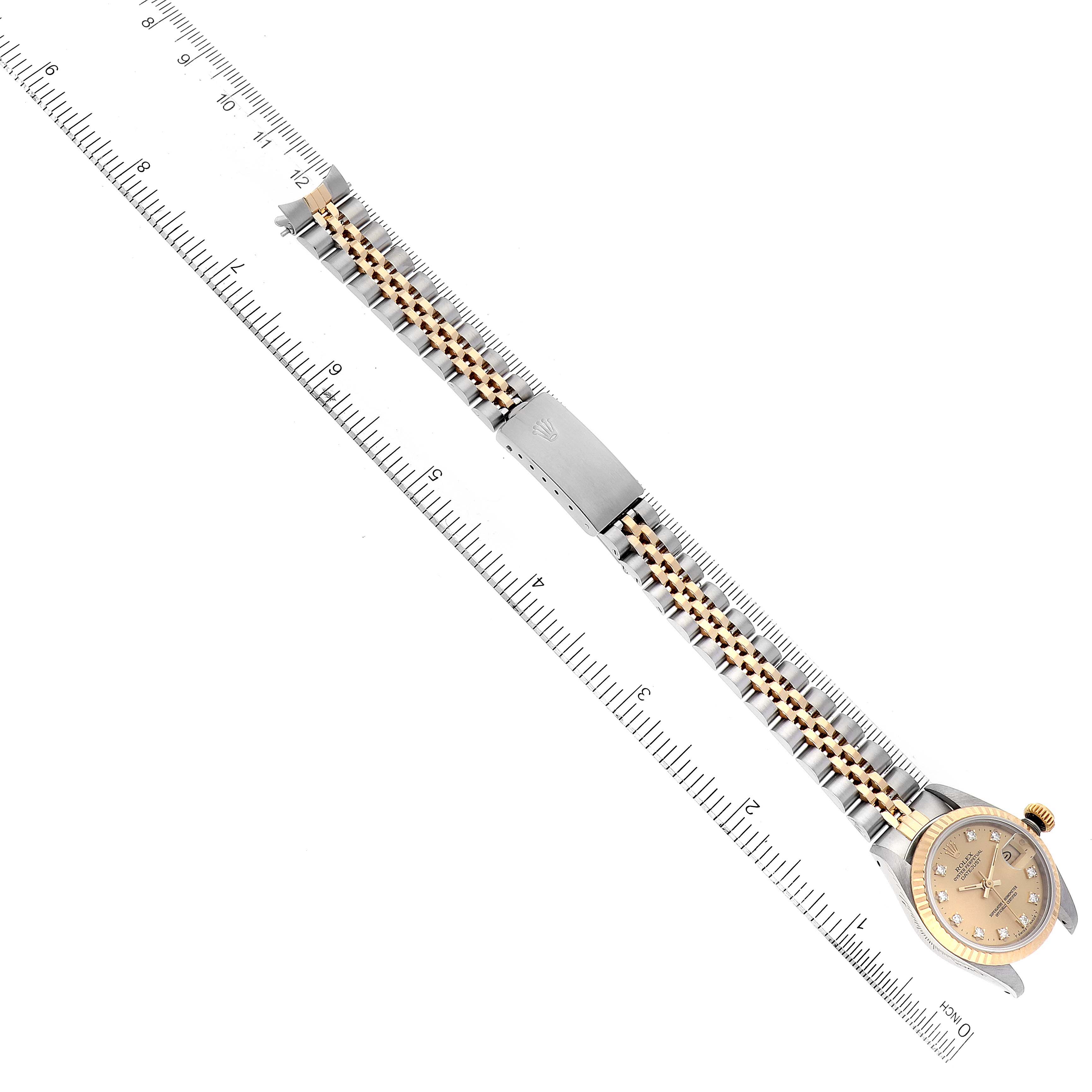 The image shows a Rolex Datejust 69173 Women's Steel and Gold (two tone) Champagne Dial 69173 Women's Steel and Gold (two tone) Champagne Dial model watch placed diagonally next to a ruler, highlighting the watch face, bezel, and bracelet.