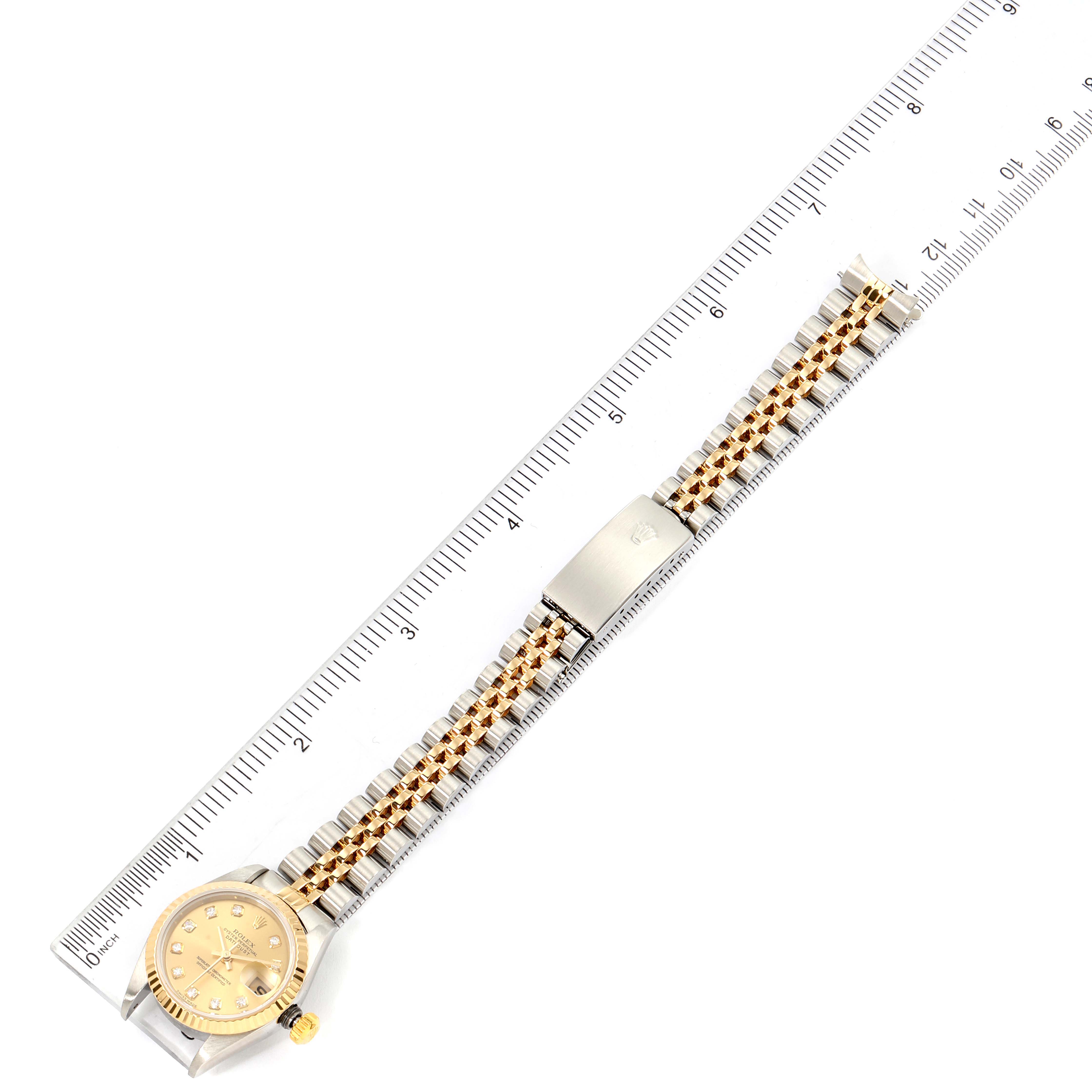 The image shows a top-down view of a Rolex Datejust 79173 Women's Steel and Gold (two tone) Champagne Dial 79173 Women's Steel and Gold (two tone) Champagne Dial watch with its bracelet aligned against a ruler.