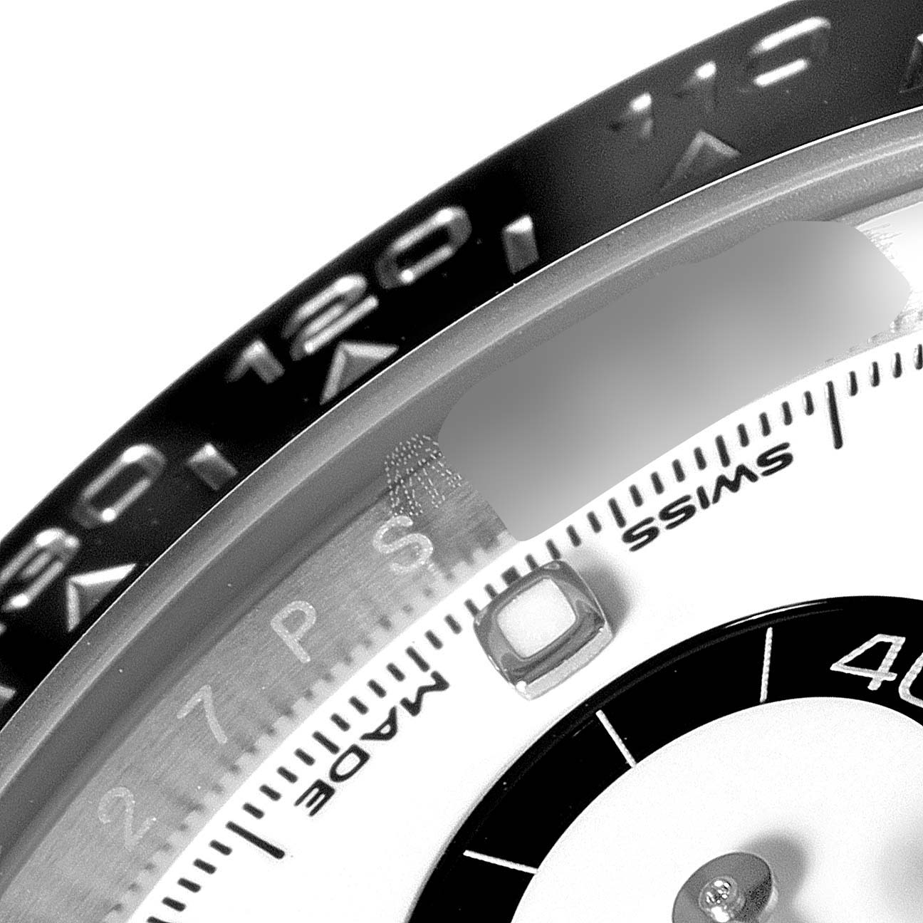 The image shows a close-up of the bezel and part of the dial of a Rolex Daytona 116500 Men's Stainless Steel White Dial 116500 Men's Stainless Steel White Dial watch.