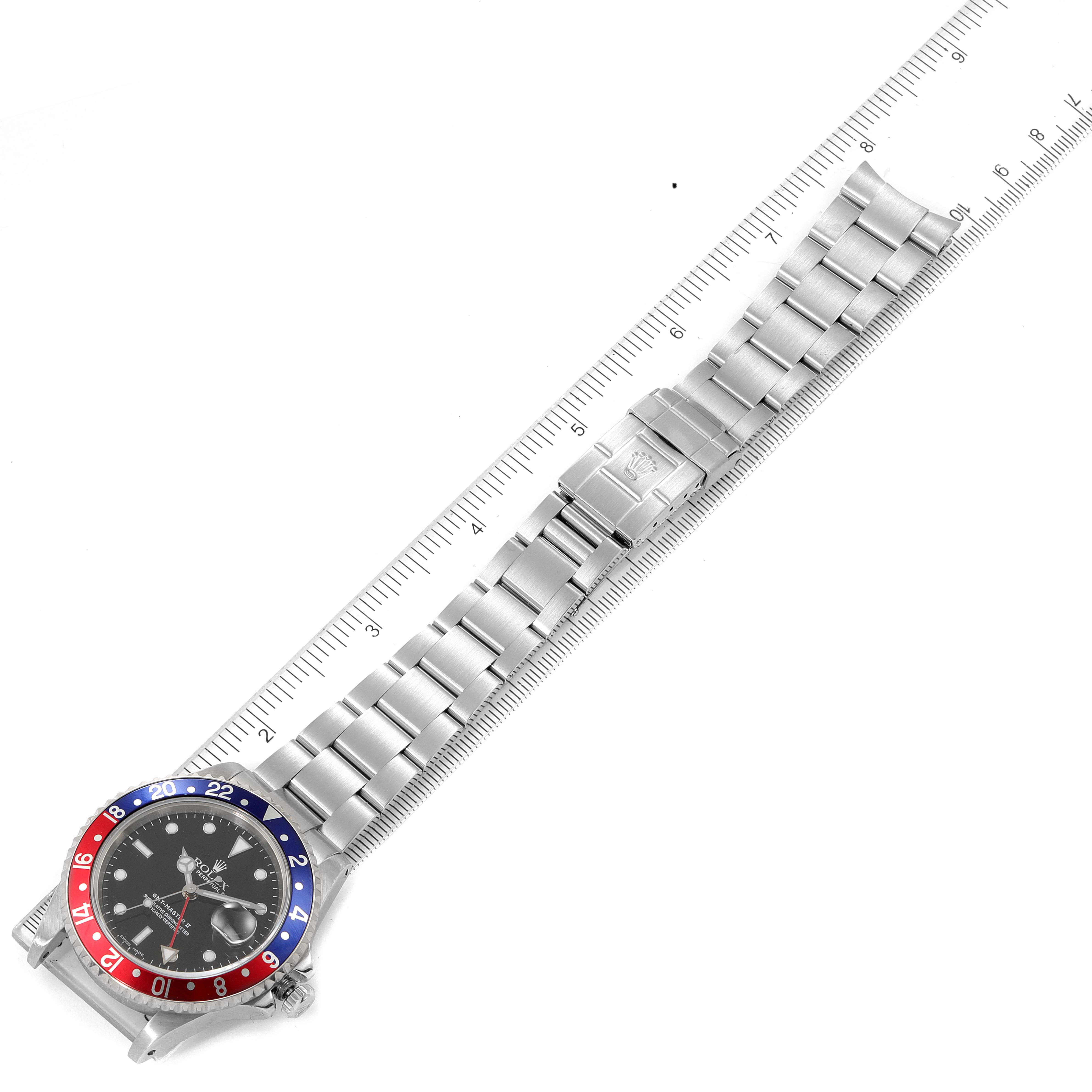 The Rolex GMT-Master 16710 Men
s Stainless Steel Black Dial 16710 Men
s Stainless Steel Black Dial watch is shown from a top-down angle, highlighting its face, bezel, and bracelet next to a ruler for scale.