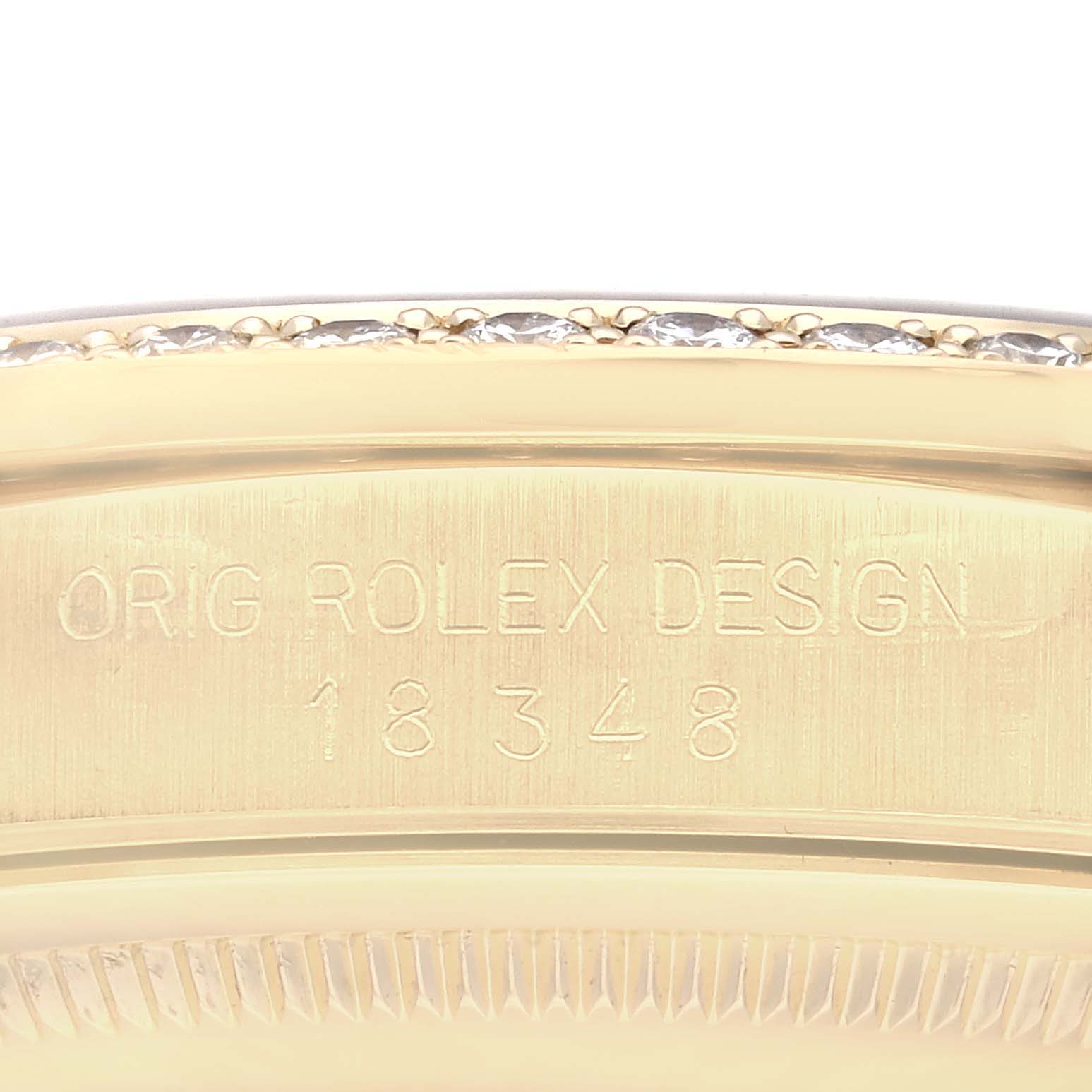 This image shows a close-up of the side of the Rolex President 18348 Men's Yellow Gold Black Dial 18348 Men's Yellow Gold Black Dial watch with engraved text and part of the bezel.
