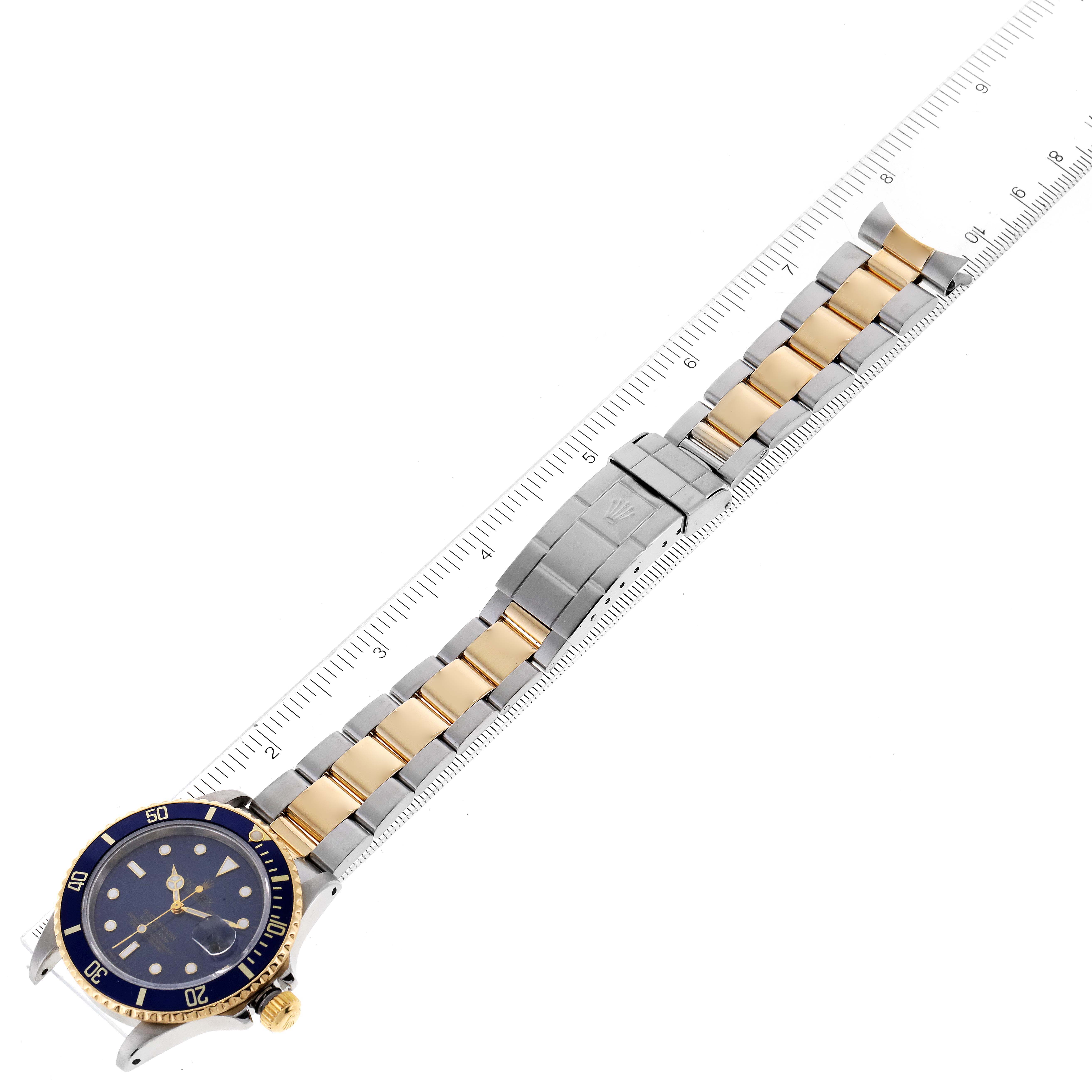 The image shows a Rolex Submariner 16803 Men
s Steel and Gold (two tone) Blue Dial 16803 Men
s Steel and Gold (two tone) Blue Dial watch laid flat with its band extended and aligned along a ruler for measurement.