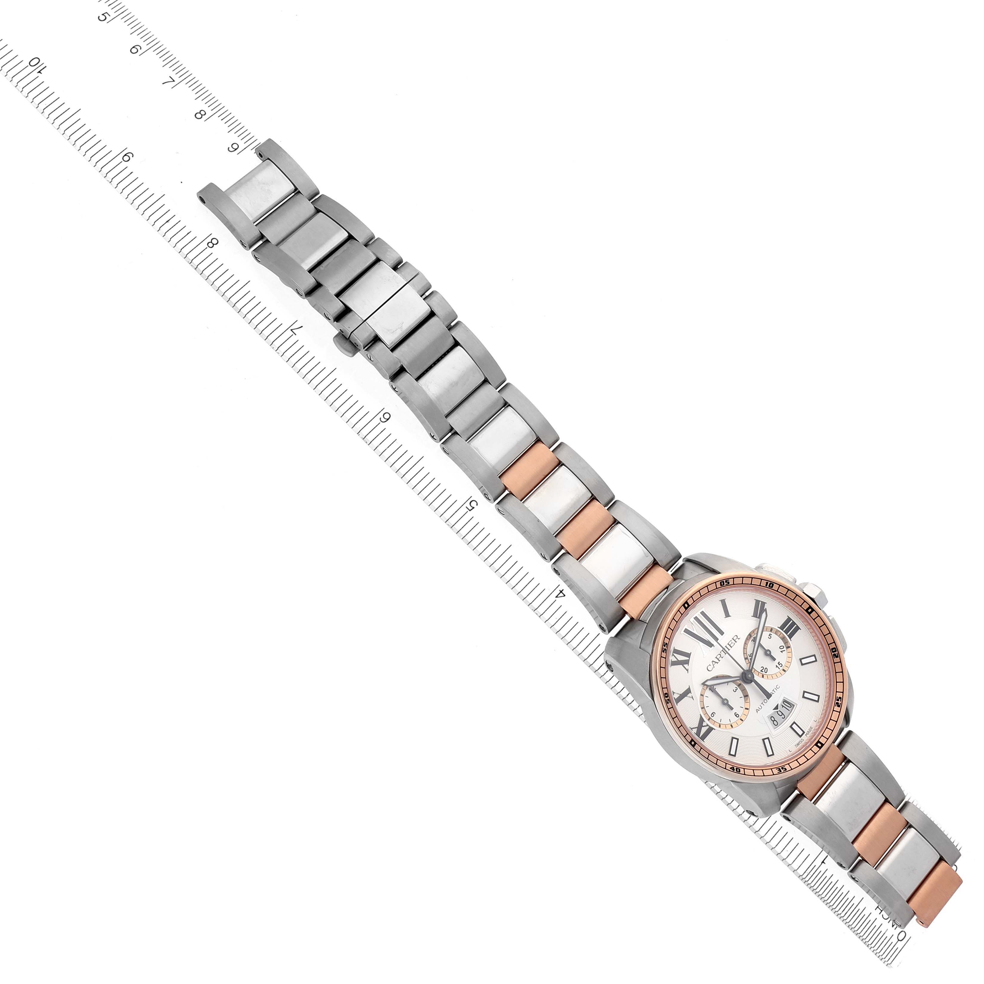 The Calibre de Cartier watch is shown diagonally with its full face and bracelet displayed alongside a measuring ruler.