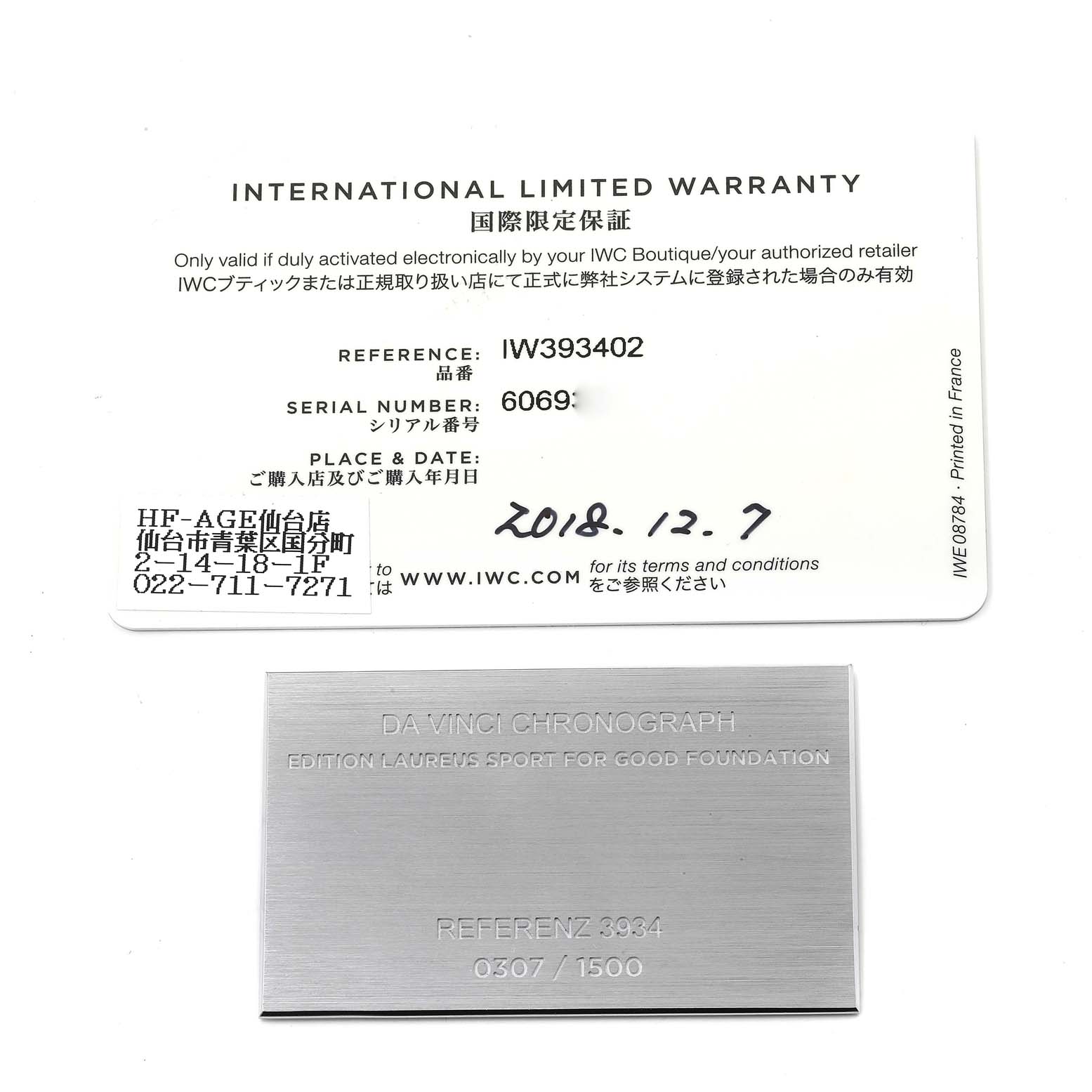 The image shows an international limited warranty card and an engraved metal plate for an IWC Da Vinci IW393402 Men's Stainless Steel Blue Dial IW393402 Men's Stainless Steel Blue Dial Chronograph watch.