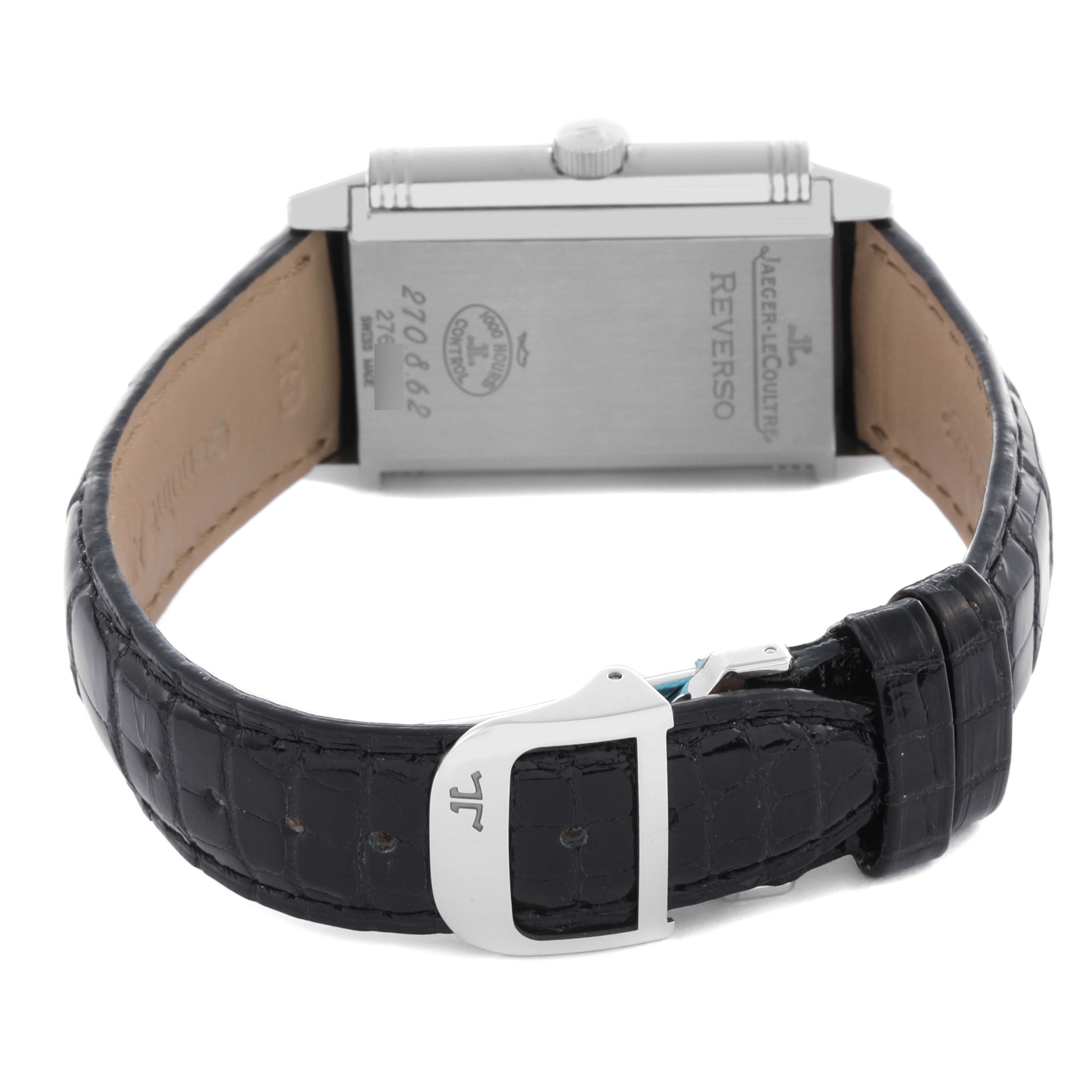 The image shows the back of a Jaeger-LeCoultre Reverso watch with its leather strap and clasp visible.