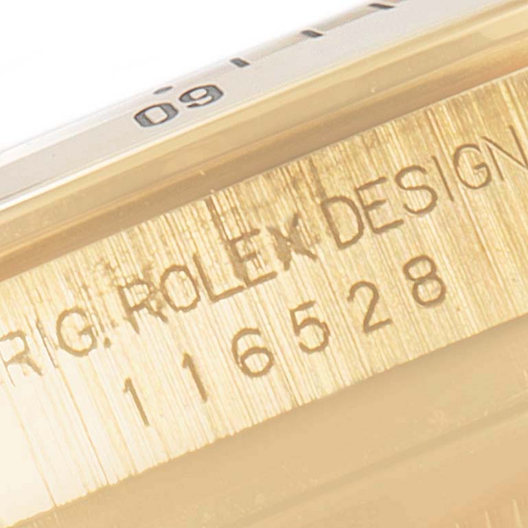 The image shows a close-up of the engraved serial number and bezel edge of a Rolex Daytona 116528 Men's Yellow Gold Black Dial 116528 Men's Yellow Gold Black Dial watch.