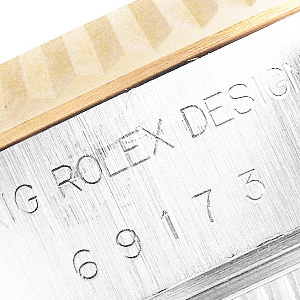 The image shows a close-up of the engraved side of a Rolex Datejust 69173 Women
s Steel and Gold (two tone) Champagne Dial 69173 Women
s Steel and Gold (two tone) Champagne Dial watch, featuring the Rolex brand name and model number.