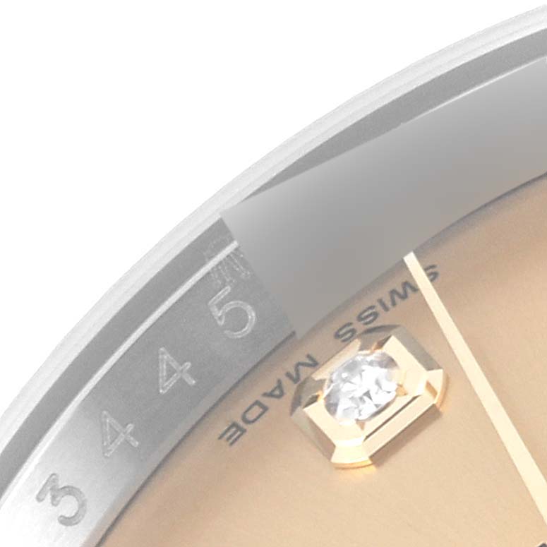 This is a close-up image of the Rolex Datejust 116233 Men's Steel and Gold (two tone) Champagne Dial 116233 Men's Steel and Gold (two tone) Champagne Dial watch, showcasing part of the bezel, dial, and one diamond marker.