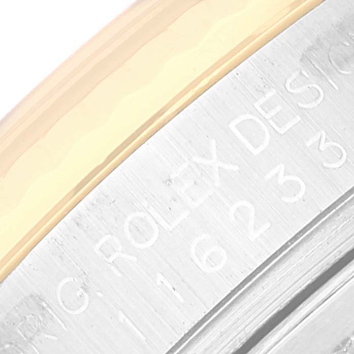 This close-up shot displays the engraved inner rim of a Rolex Datejust 116233 Men's Steel and Gold (two tone) White Dial 116233 Men's Steel and Gold (two tone) White Dial watch, showcasing part of its bezel and case number.