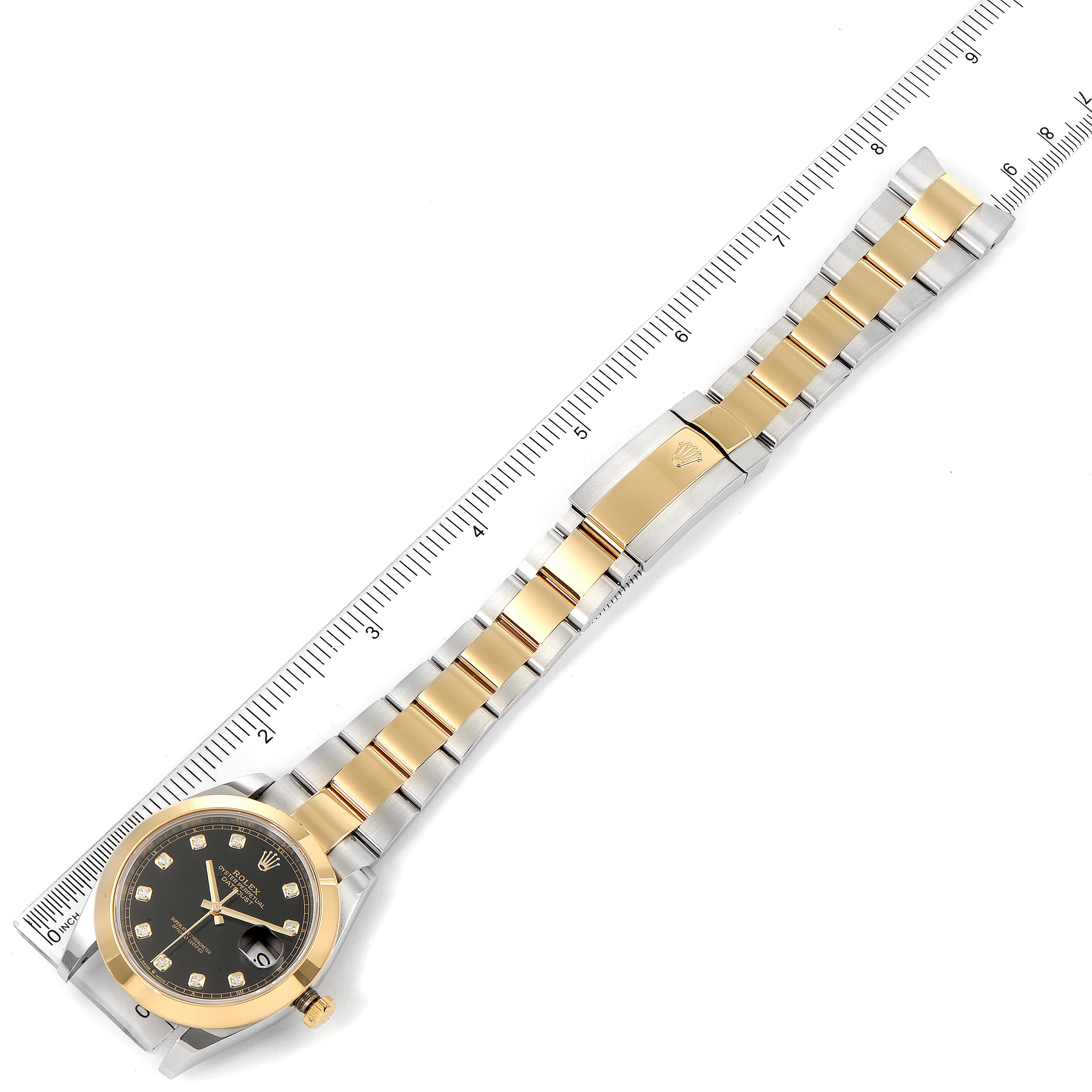 The image shows a top view of a Rolex Datejust 41 126303 Men's Steel and Gold (two tone) Black Dial 126303 Men's Steel and Gold (two tone) Black Dial watch including its dial, case, and two-tone bracelet alongside a measuring ruler.