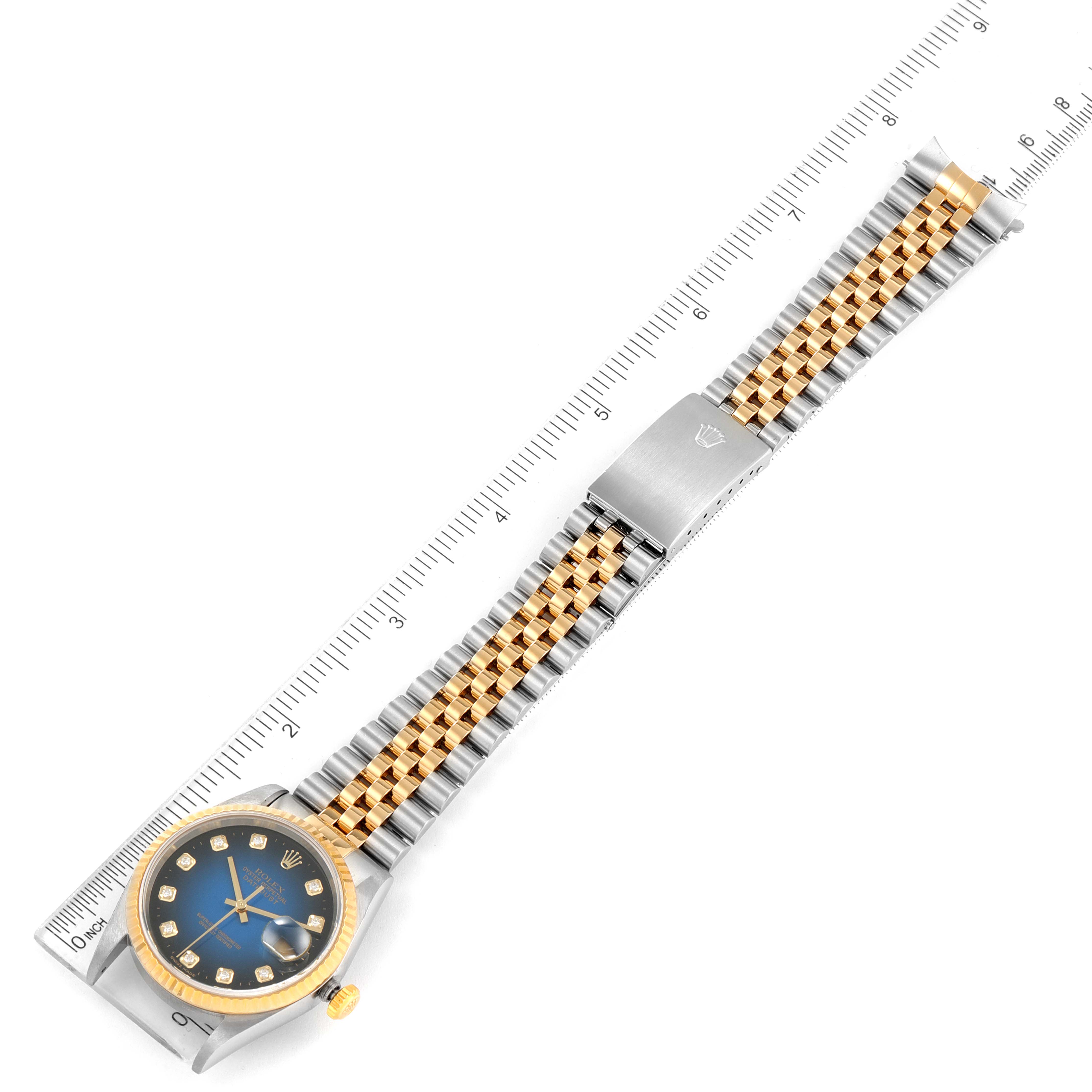 This image displays a top-down view of the Rolex Datejust 16233 Men's Steel and Gold (two tone) Blue Dial 16233 Men's Steel and Gold (two tone) Blue Dial watch showing the face, bezel, bracelet, and clasp against a ruler for measurement.