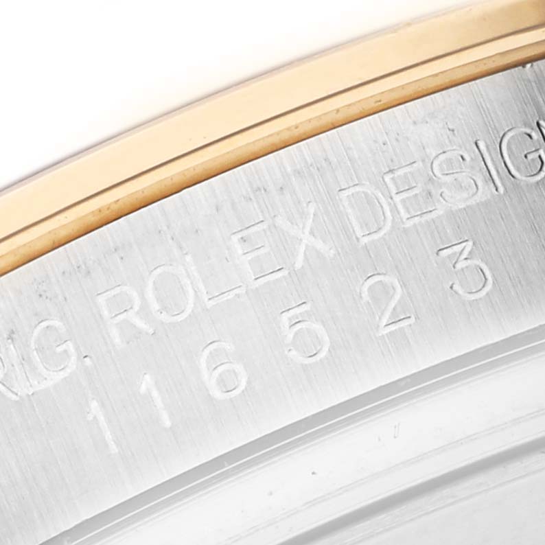 The image shows a close-up of the engraved side of a Rolex Daytona 116523 Men's Steel and Gold (two tone) Silver Dial 116523 Men's Steel and Gold (two tone) Silver Dial watch case, highlighting the model number and design markings.