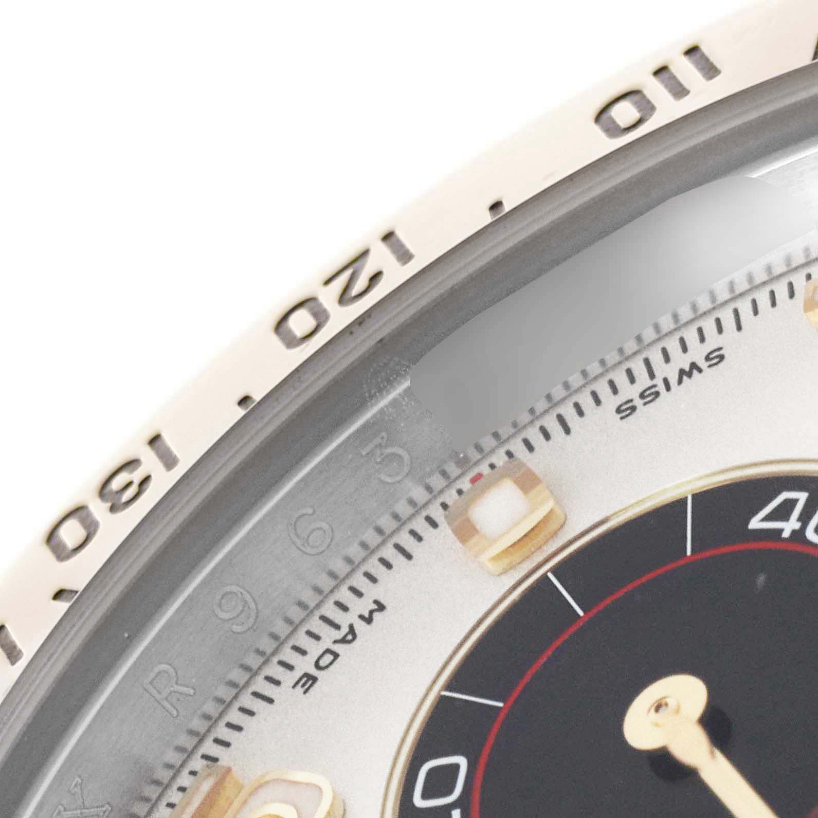 This close-up image shows the bezel and a portion of the dial of a Rolex Daytona 116523 Men's Steel and Gold (two tone) Silver Dial 116523 Men's Steel and Gold (two tone) Silver Dial watch.