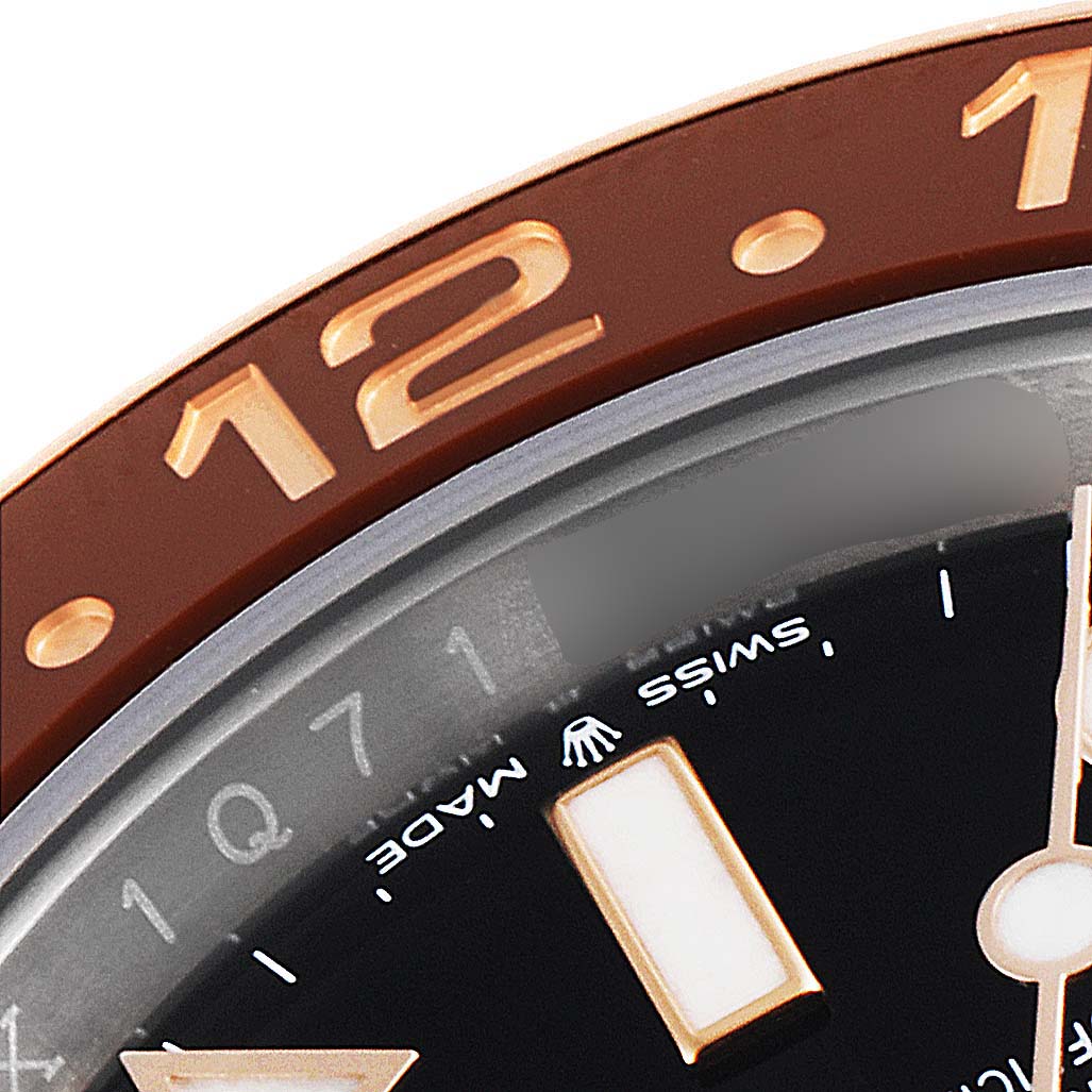This close-up angled image shows part of the bezel and dial of the Rolex GMT-Master 126711 Men
s Rose Gold Black Dial 126711 Men
s Rose Gold Black Dial watch, featuring the number 12 on the bezel.