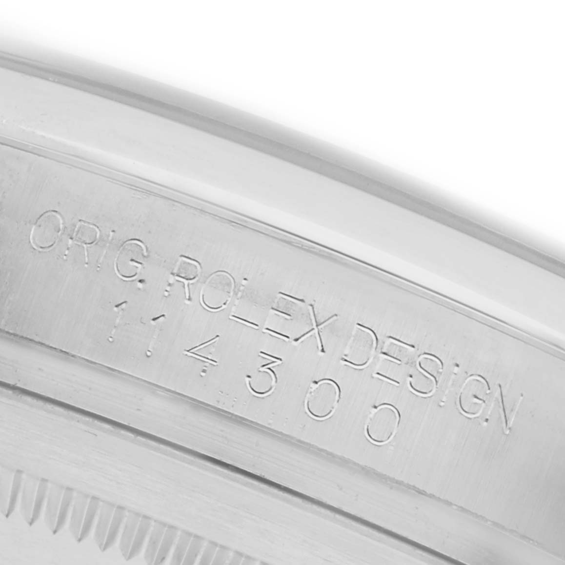 The image shows a close-up angle of the case side of a Rolex Oyster Perpetual 114300 Men's Stainless Steel Blue Dial 114300 Men's Stainless Steel Blue Dial, focusing on the engraved model number.