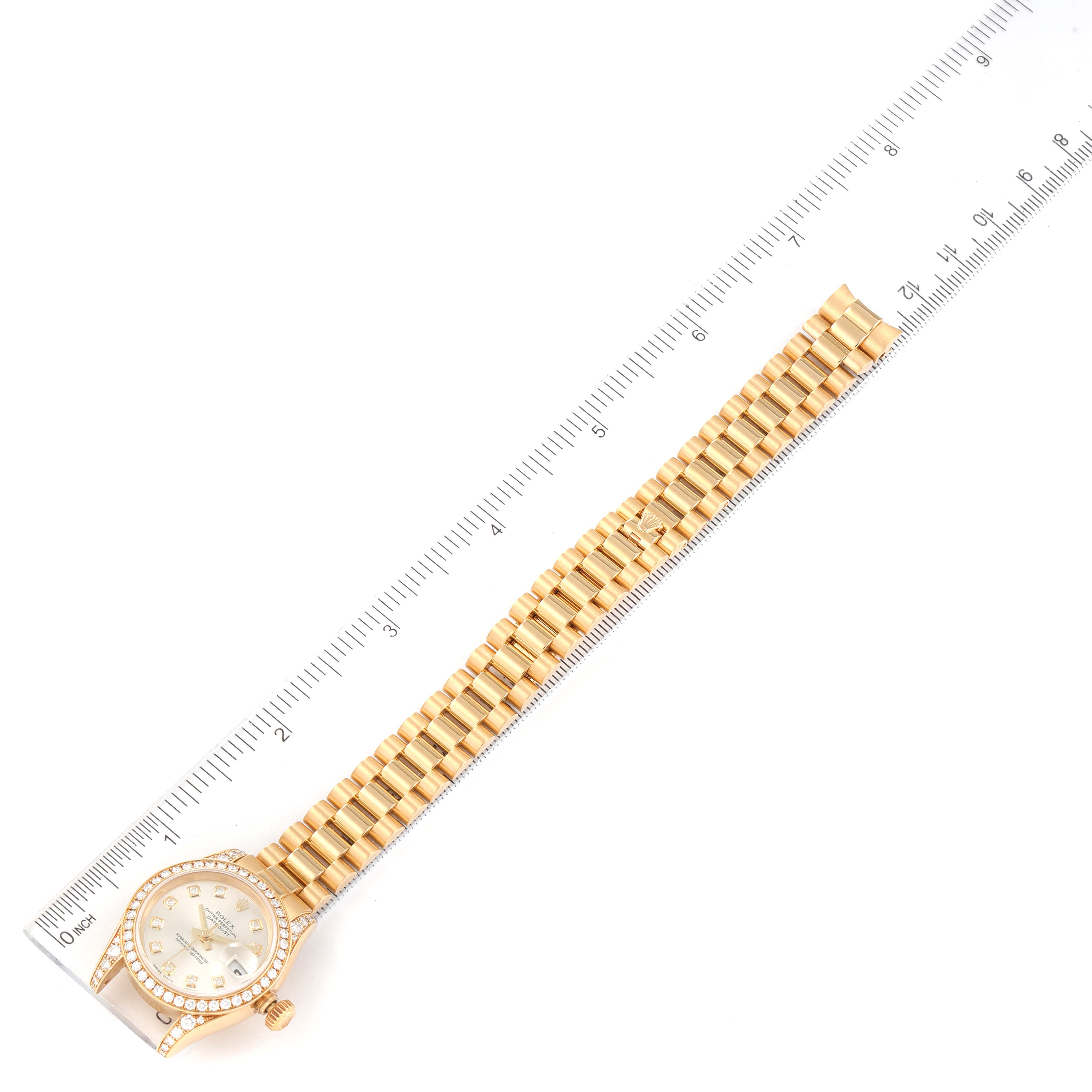 This image shows a top-down view of a Rolex President 179158 Women's Yellow Gold Silver Dial 179158 Women's Yellow Gold Silver Dial model watch with its bracelet and a ruler for scale.