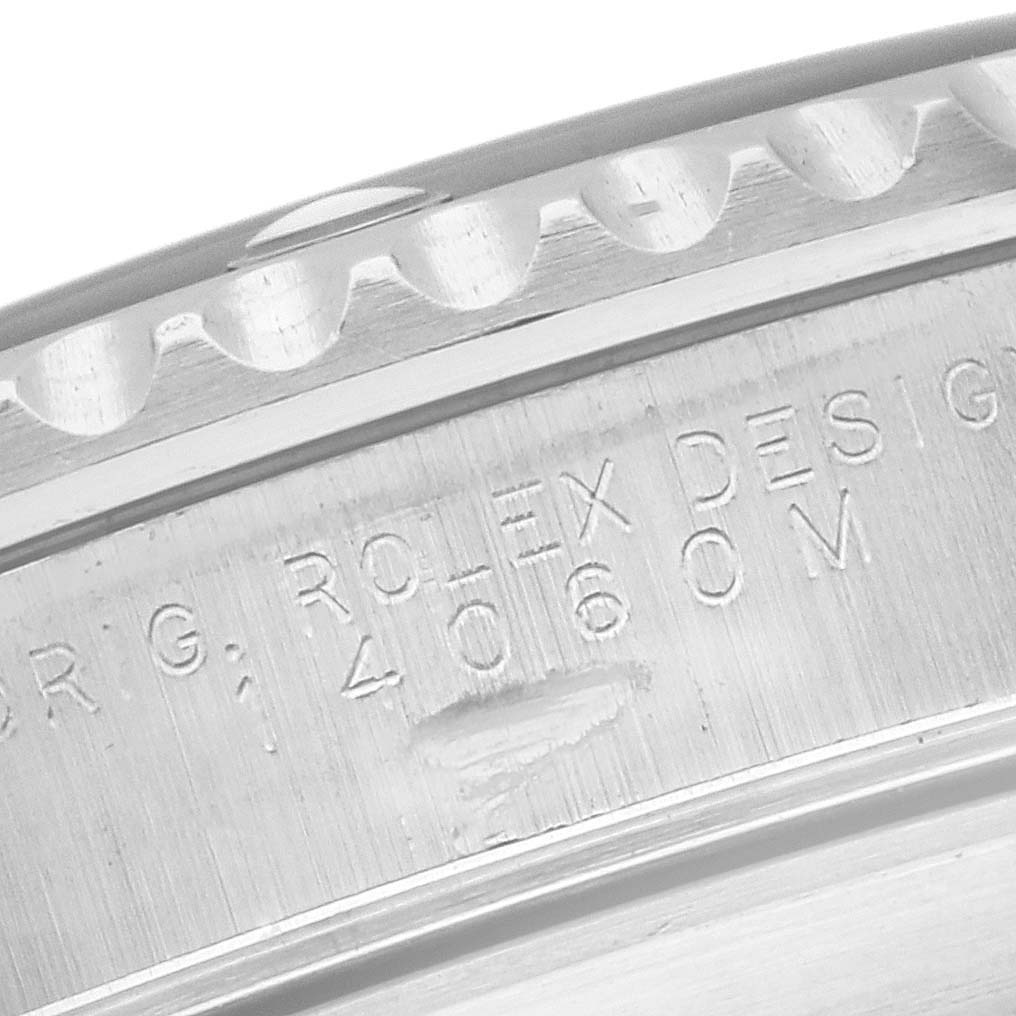 The image shows a close-up of the edge and bezel of a Rolex Submariner 14060M Men's Stainless Steel Black Dial 14060M Men's Stainless Steel Black Dial, featuring engraved text.