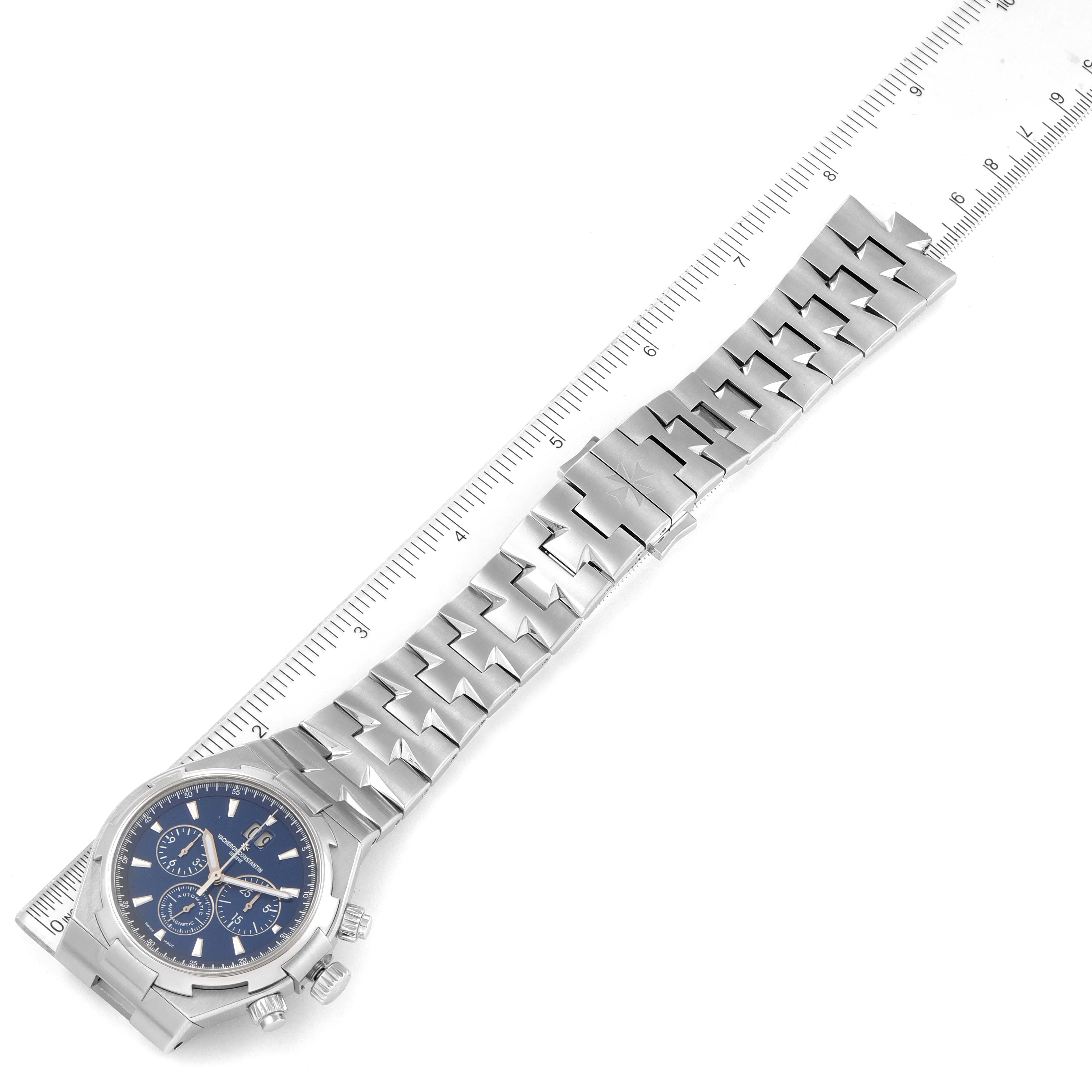 The Vacheron Constantin Overseas 49150.B01A.9097 Men's Stainless Steel Blue Dial 49150.B01A.9097 Men's Stainless Steel Blue Dial watch is shown from a top-down angle with its bracelet fully extended alongside a ruler.