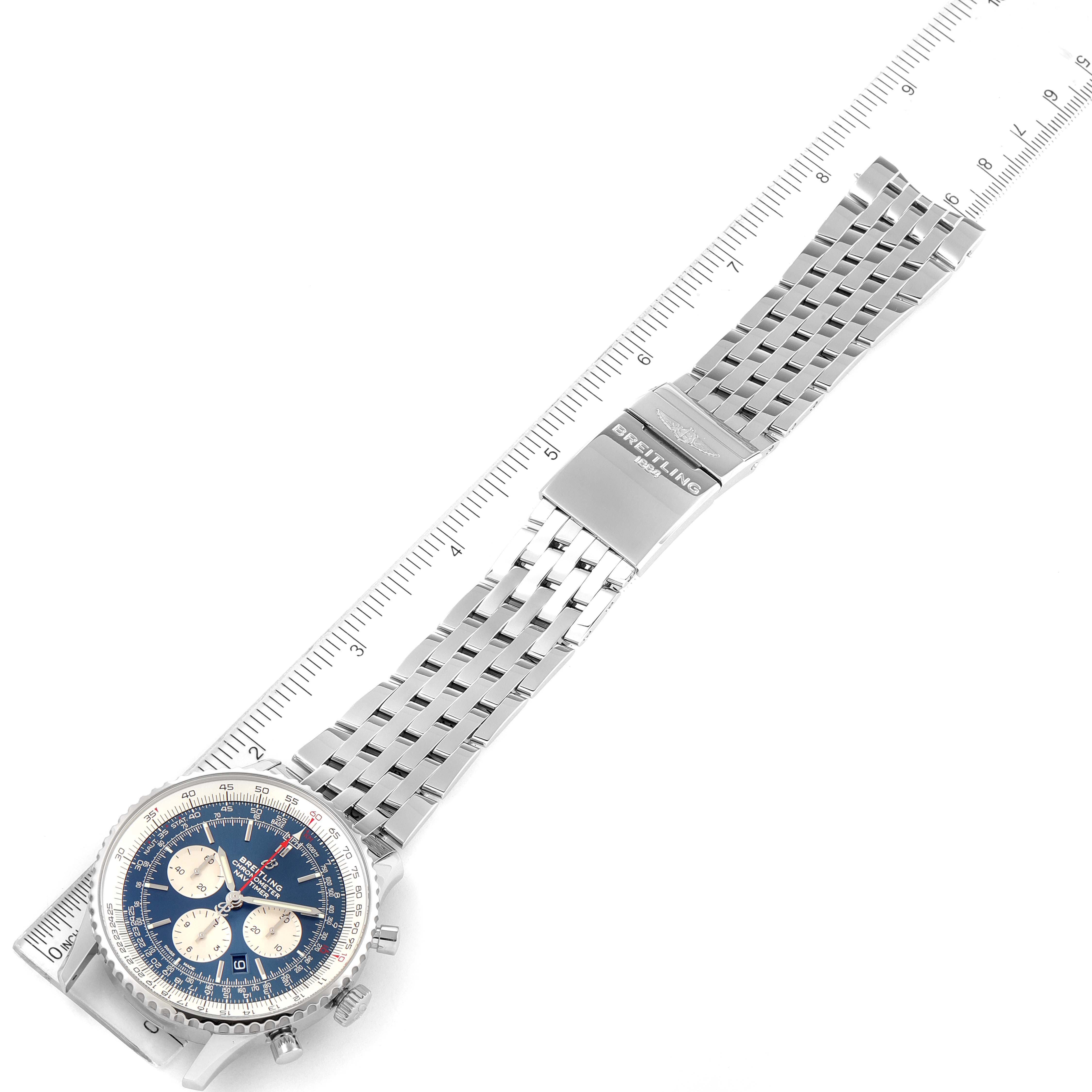 The image shows a top-down view of a Breitling Navitimer AB0127211C1A1 Men's Stainless Steel Blue Dial AB0127211C1A1 Men's Stainless Steel Blue Dial watch, showcasing its face, bezel, and metal bracelet alongside a ruler.