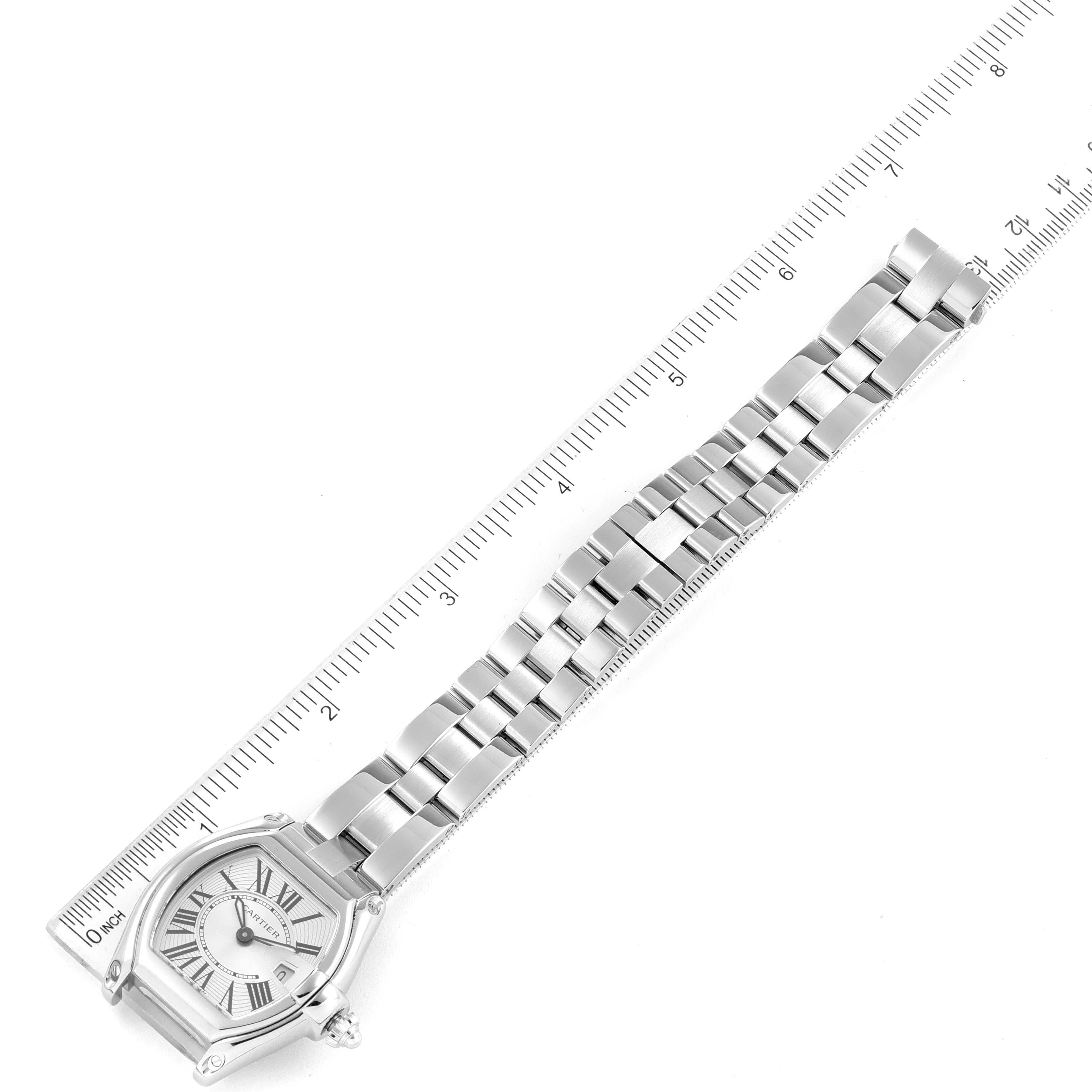 The image shows an aerial view of the Cartier Roadster W62016V3 Women
s Stainless Steel Silver Dial W62016V3 Women
s Stainless Steel Silver Dial watch, including the face, bezel, and bracelet set against a measuring scale.