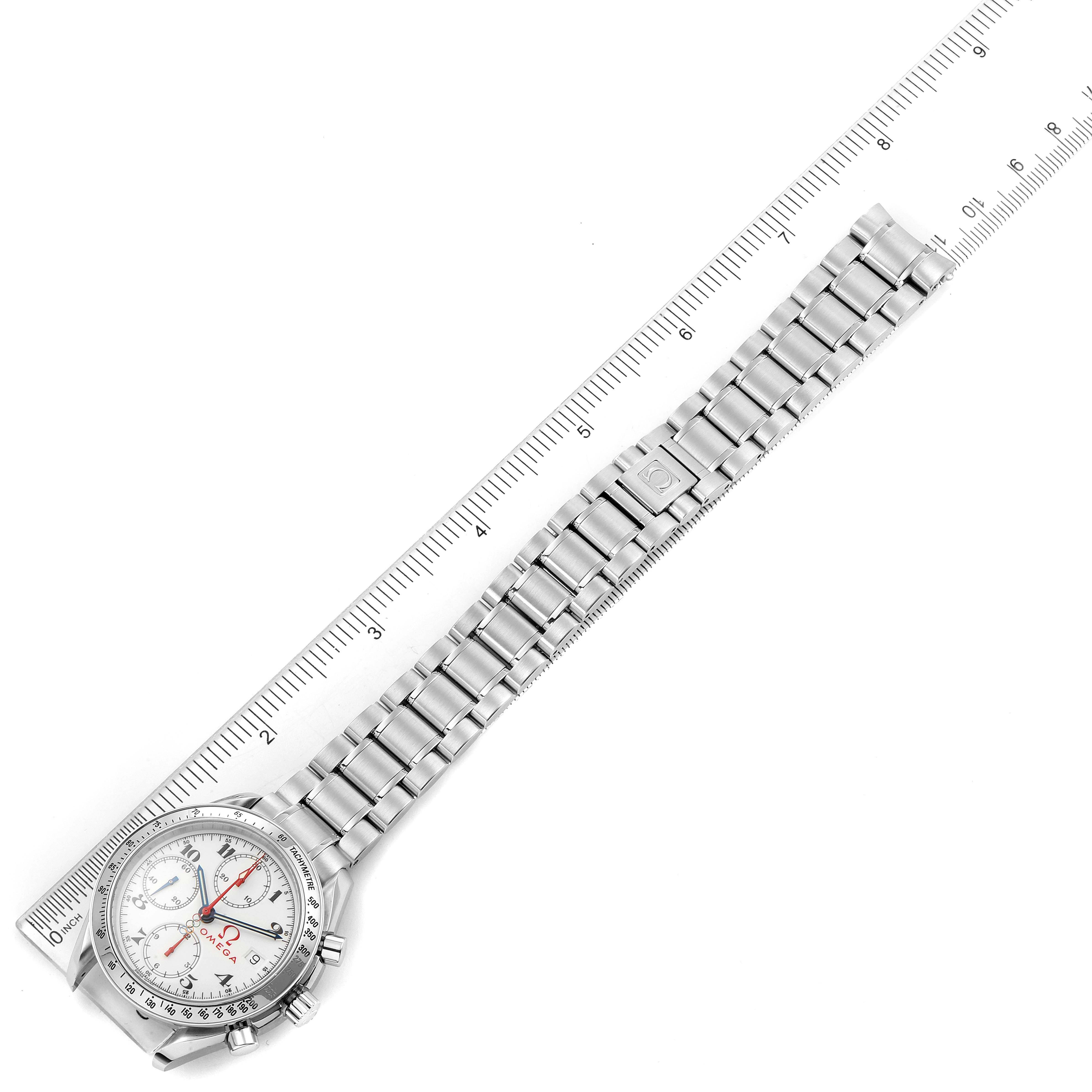 This image shows an Omega Speedmaster 3515.20.00 Men
s Stainless Steel White Dial 3515.20.00 Men
s Stainless Steel White Dial watch laid flat with its bracelet extended, positioned alongside a ruler.