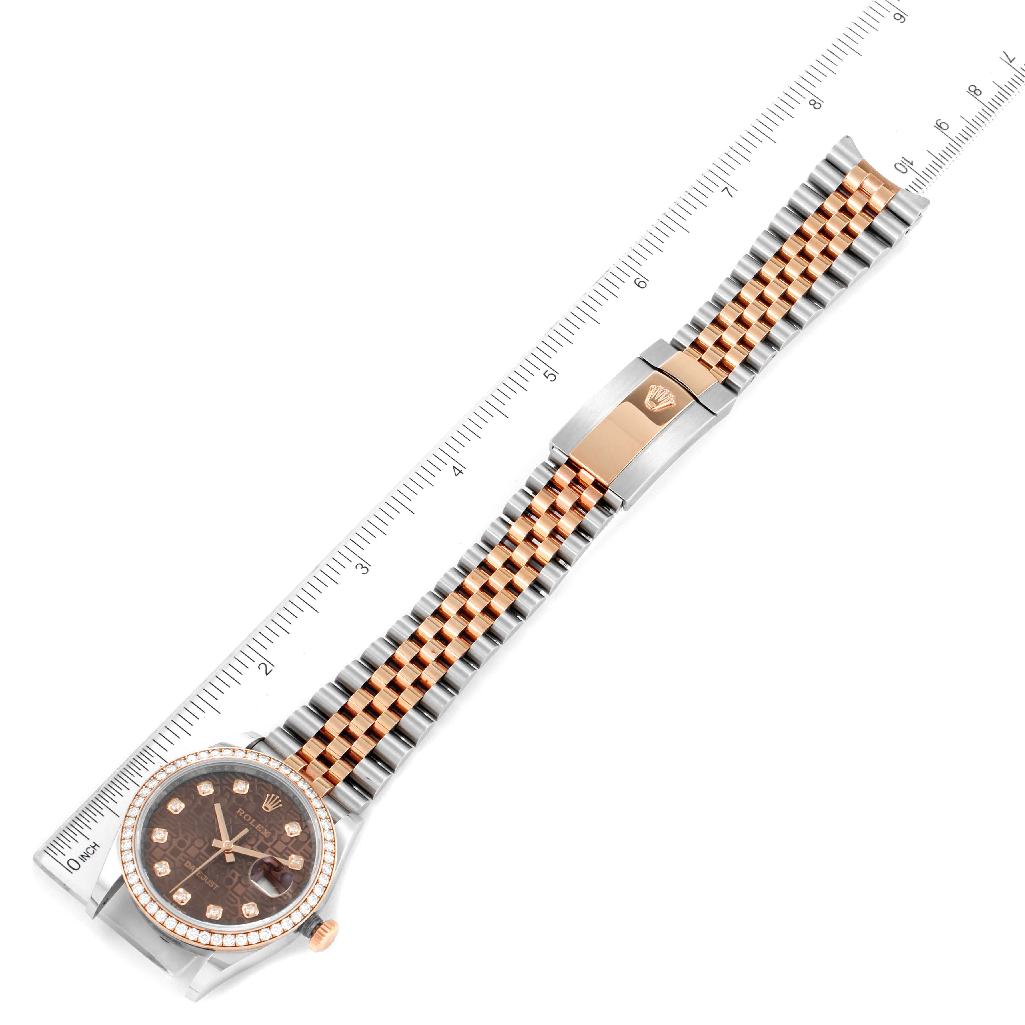 The Rolex Datejust 126281 Men's Steel and Gold (two tone) Brown Dial 126281 Men's Steel and Gold (two tone) Brown Dial watch is shown from an aerial view, displaying the face, bezel, bracelet, and clasp next to a ruler.