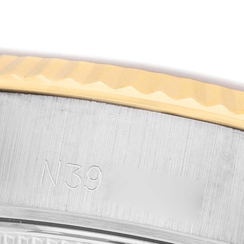 The image shows a close-up of the side engraving and fluted bezel of a Rolex Datejust 69173 Women's Steel and Gold (two tone) Champagne Dial watch.