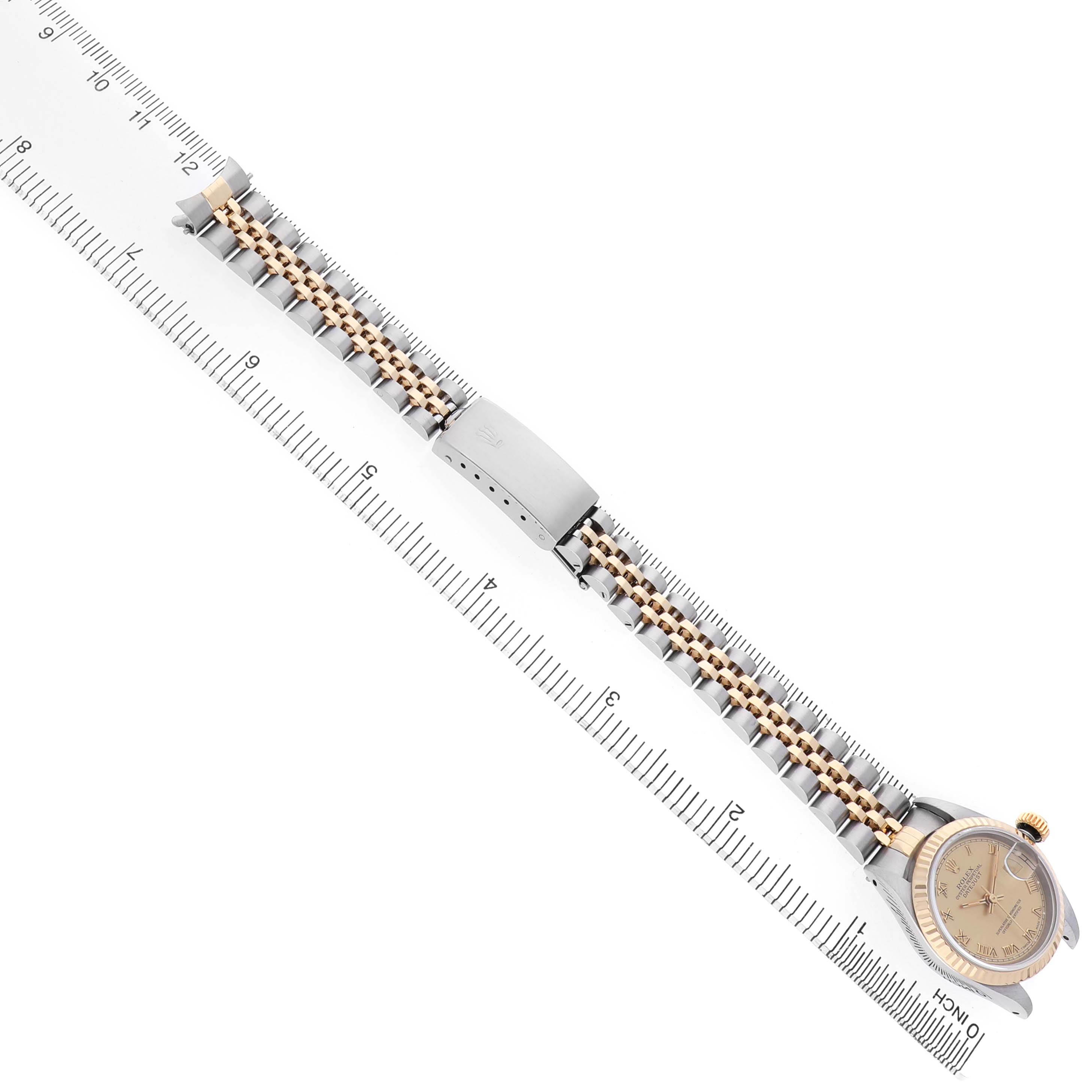 The Rolex Datejust 69173 Women's Steel and Gold (two tone) Champagne Dial watch is shown from a top angle, displaying its face, bracelet, and clasp, alongside a ruler for scale.