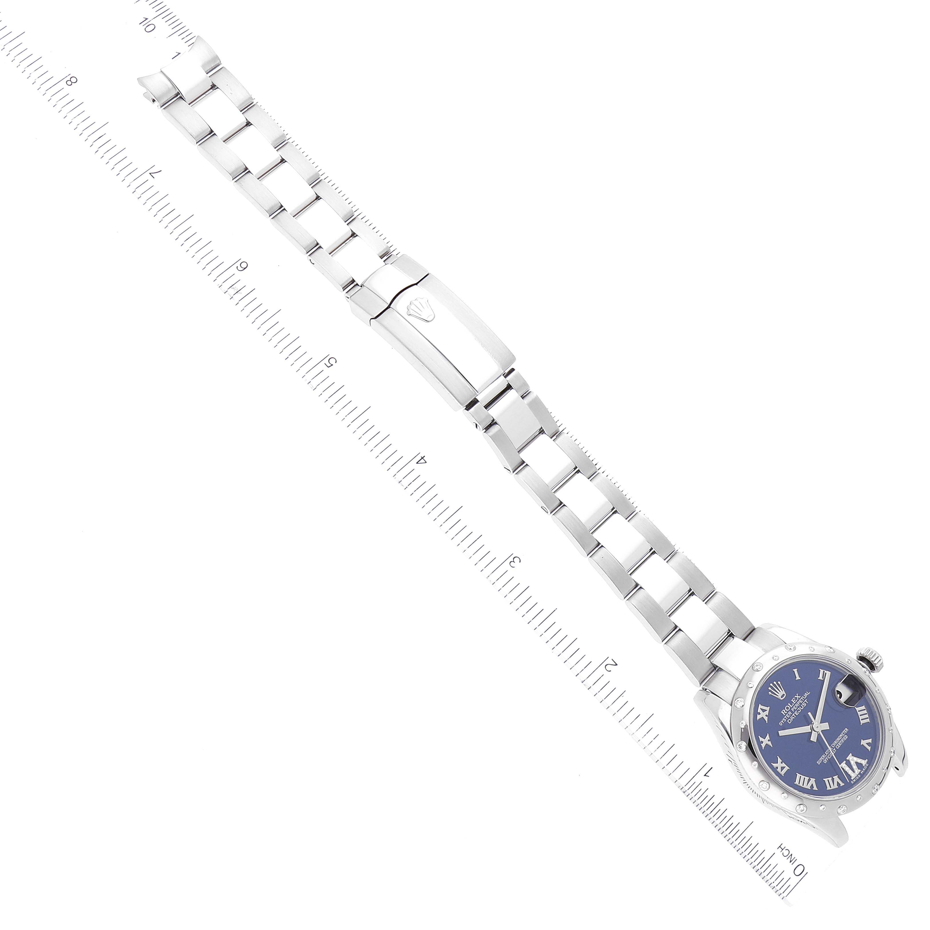 This image shows a full view of a Rolex Mid-Size 178344 Women
s Stainless Steel Blue Dial 178344 Women
s Stainless Steel Blue Dial watch, displaying its band, clasp, and blue dial face, laid flat with rulers beside it.