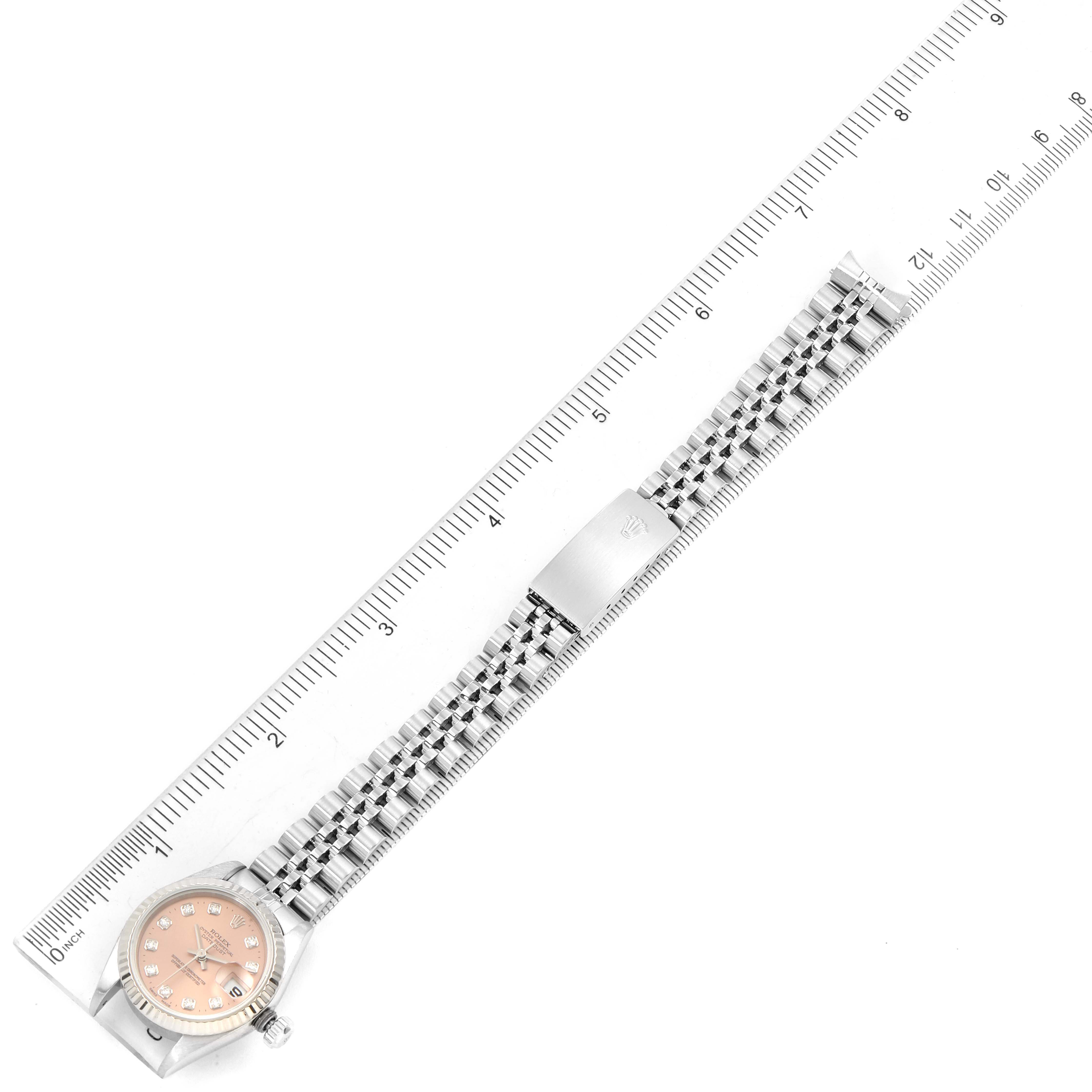 The Rolex Datejust 79174 Women's Stainless Steel Pink Dial 79174 Women's Stainless Steel Pink Dial watch is shown laying flat with its full metal bracelet extended alongside a ruler for scale.