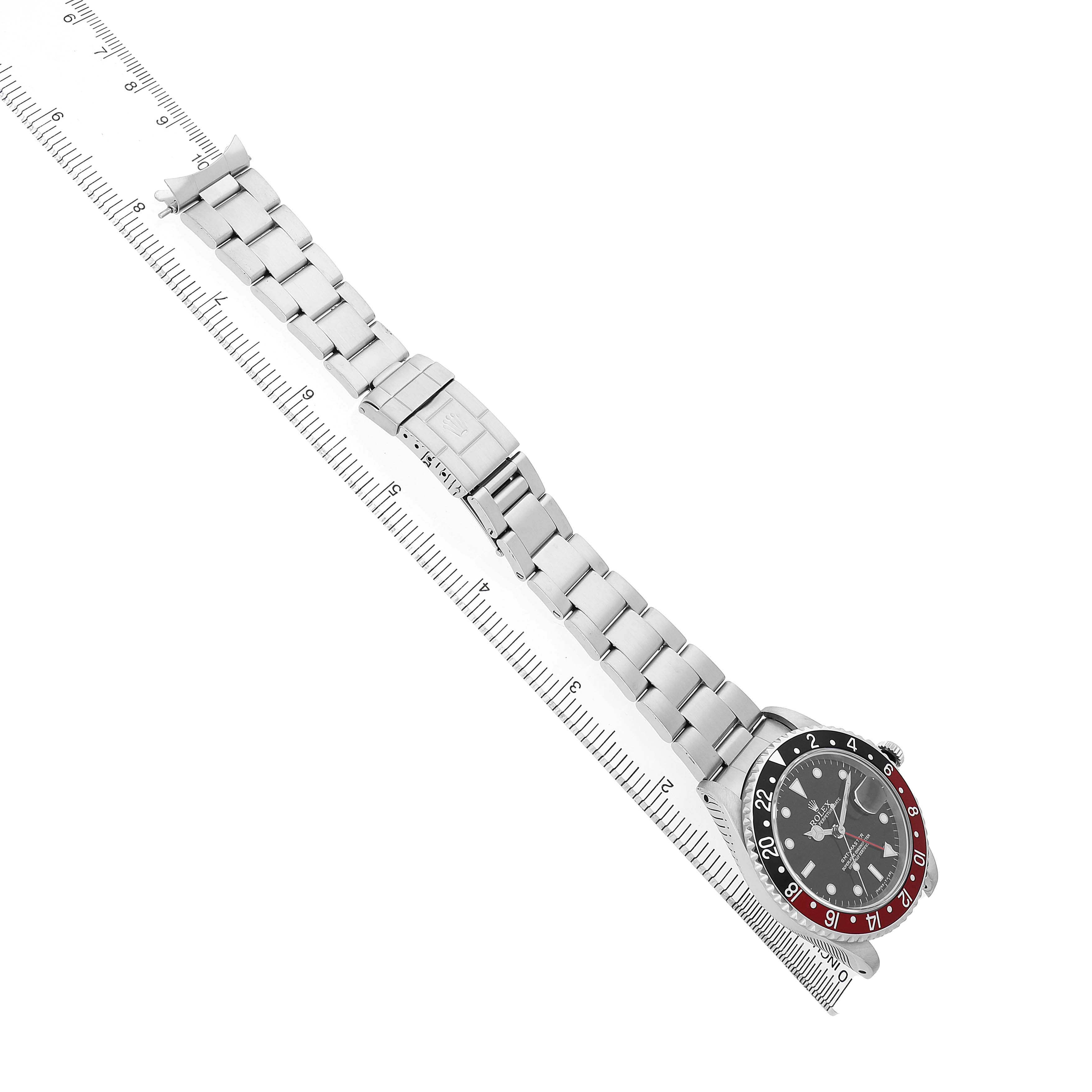 The Rolex GMT-Master 16700 Men's Stainless Steel Black Dial is shown at an angle, displaying the face, bezel, and entire bracelet, alongside a ruler for scale.