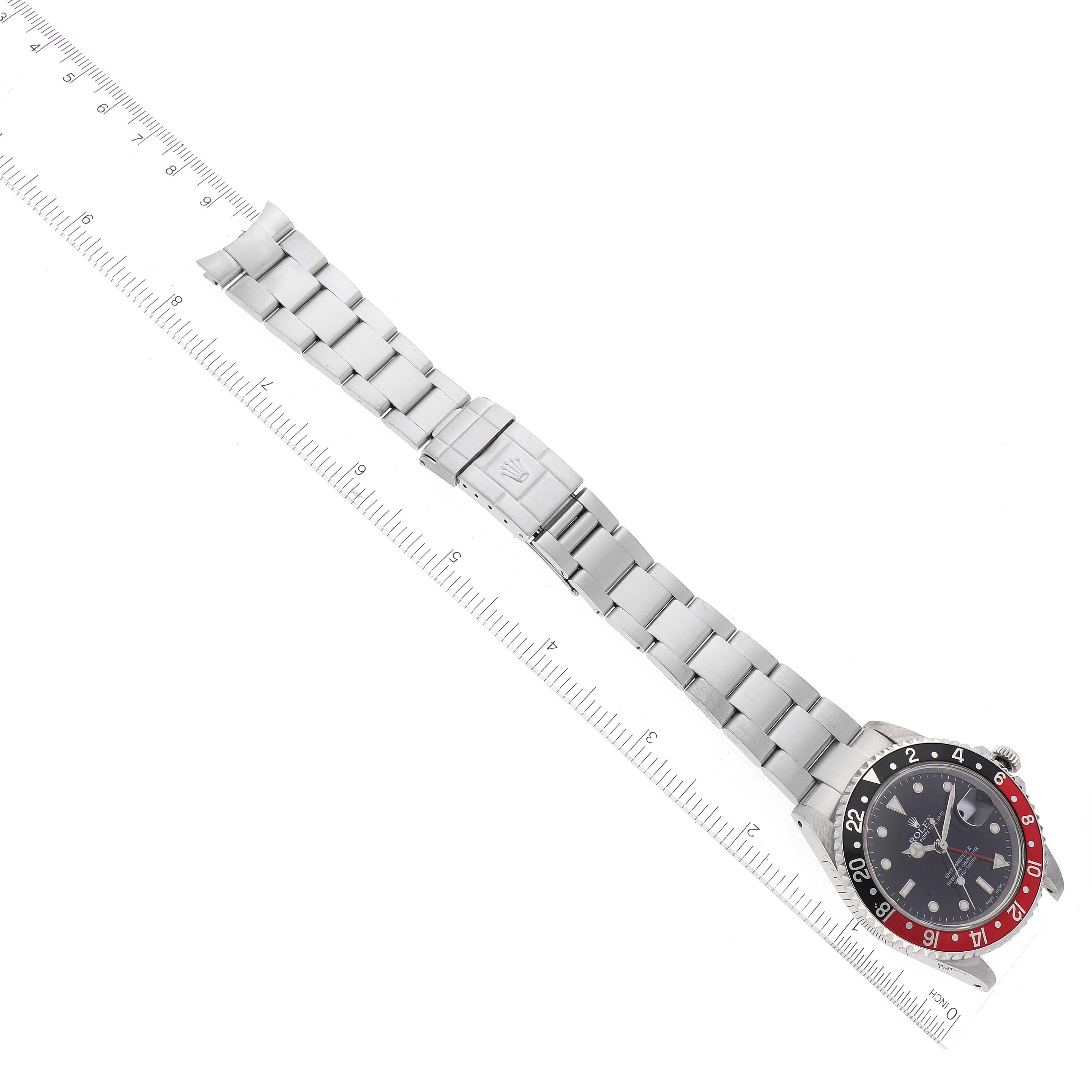 The image shows a top-down view of a Rolex GMT-Master 16710 Men's Stainless Steel Black Dial 16710 Men's Stainless Steel Black Dial watch, highlighting the face, bezel, bracelet, and clasp against a ruler for scale.