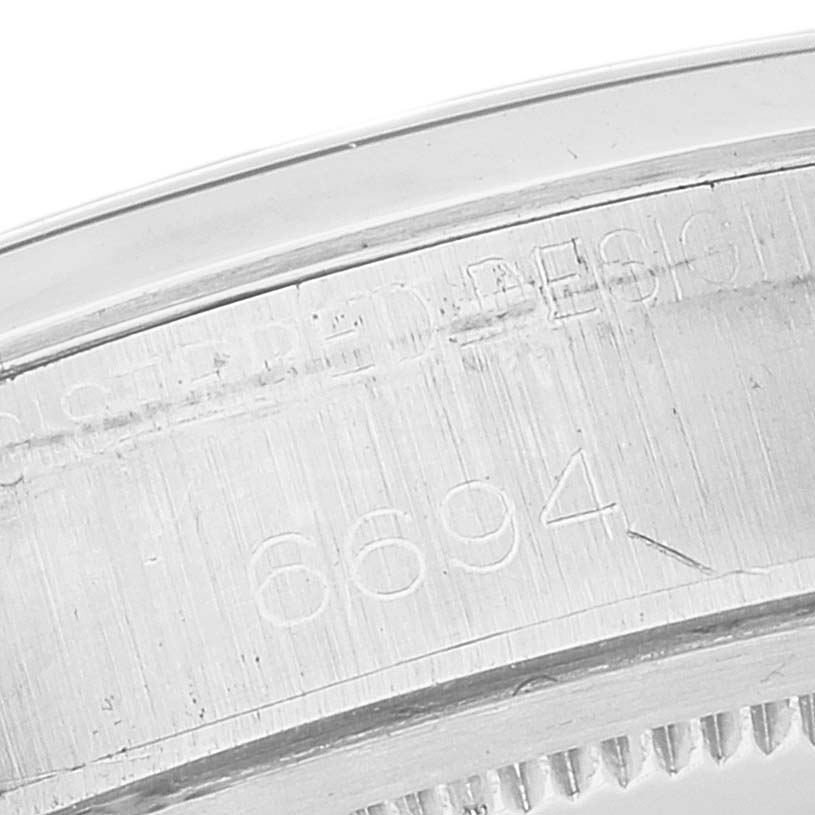 This image shows a close-up of the engraved serial number on the side of the bezel of a Rolex Vintage Collection 6694 Men's Stainless Steel Black Dial 6694 Men's Stainless Steel Black Dial model watch.