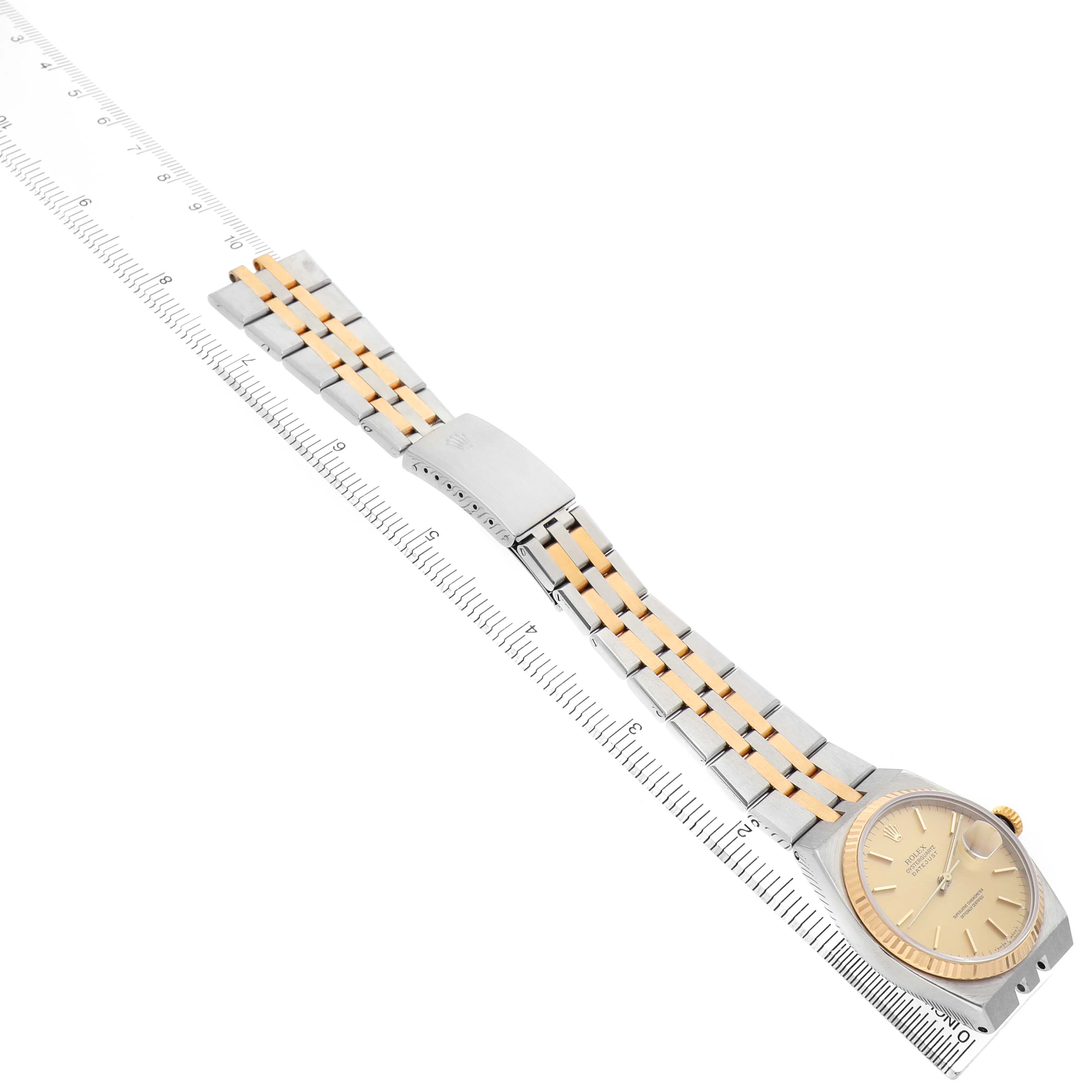 The Rolex Oysterquartz 17013 Men's Steel and Gold (two tone) Champagne Dial watch is shown at a side angle, highlighting the gold and silver bracelet and bezel on a ruler for scale.