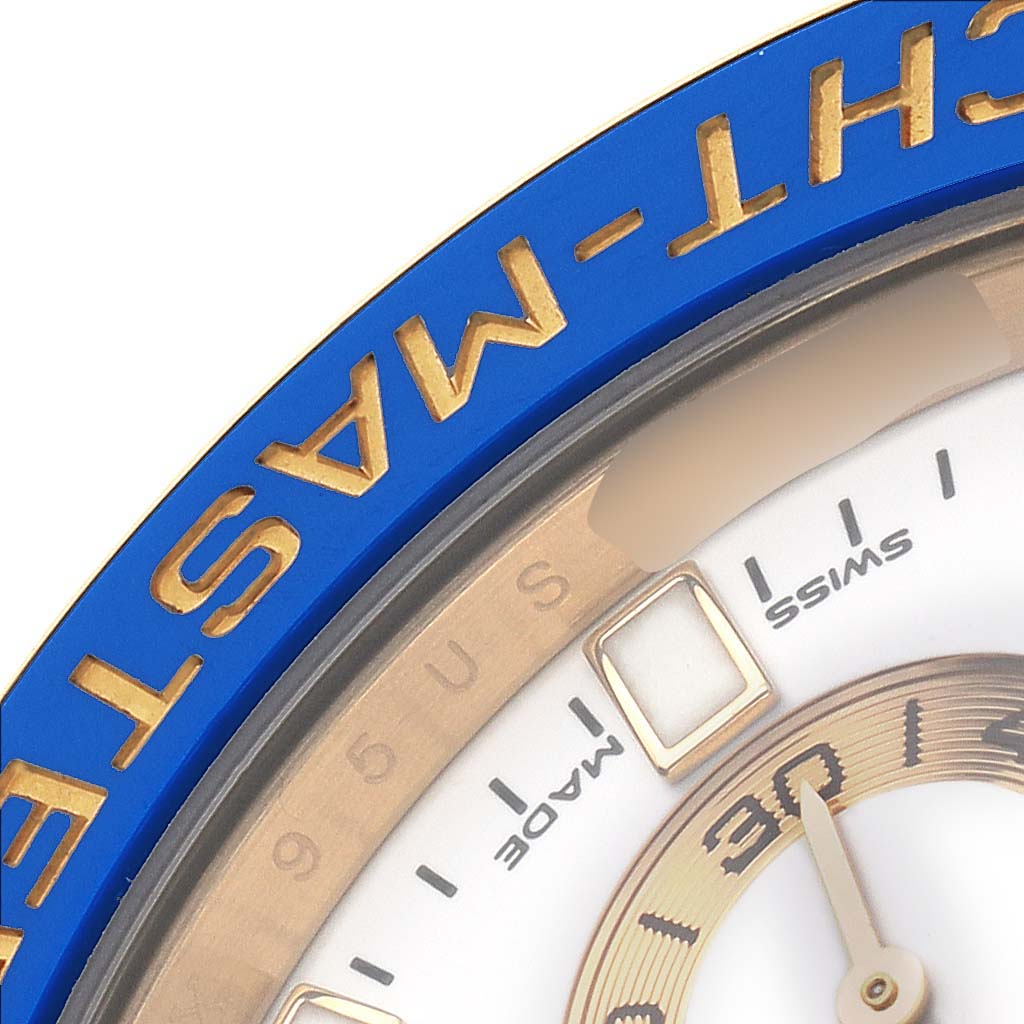 The image shows a close-up angle of the Rolex Yacht-Master 116688M Men's Yellow Gold White Dial watch, highlighting the blue bezel and partial dial.