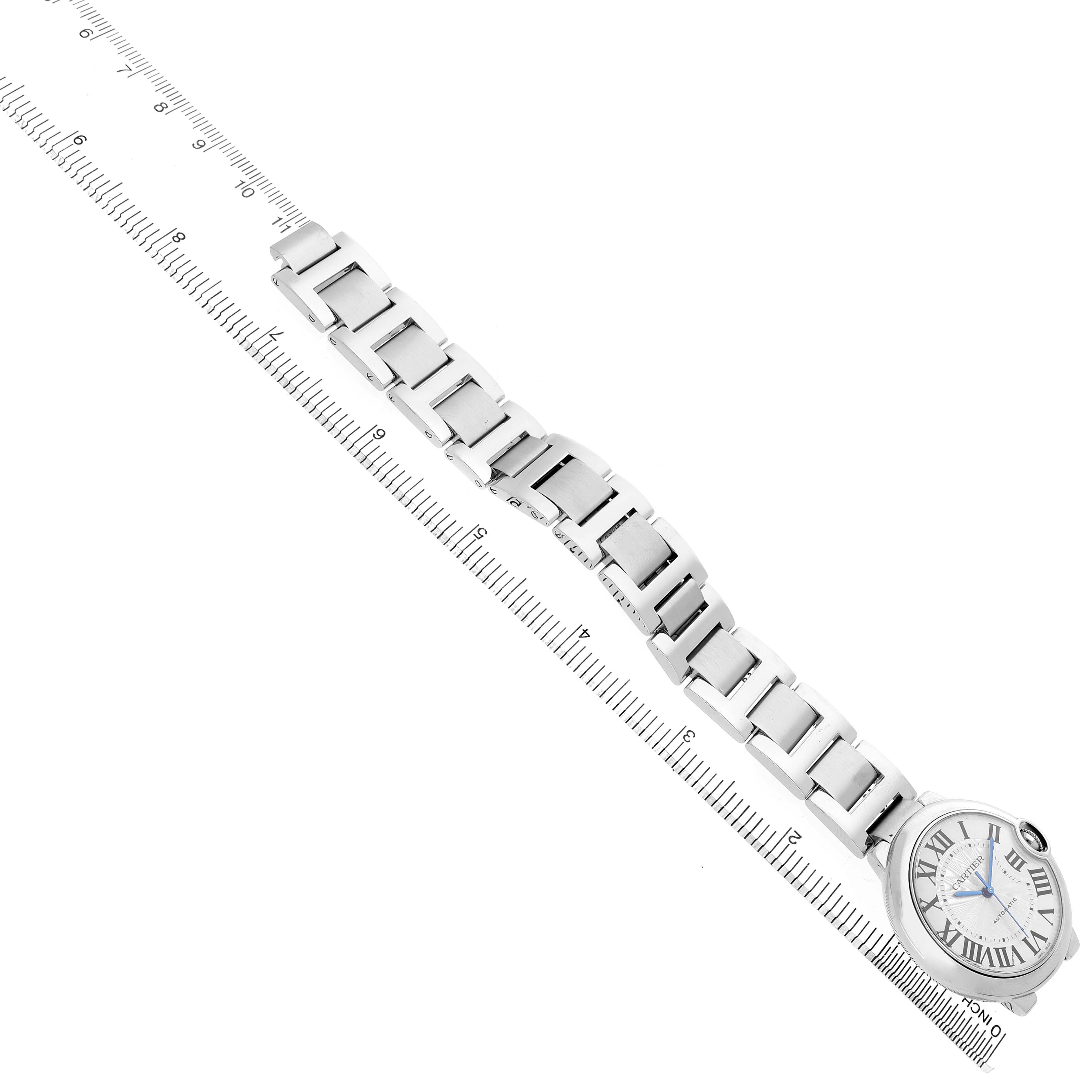 The Cartier Ballon Bleu W6920046 Women's Stainless Steel Silver Dial watch is shown from a top-down angle, displaying the bracelet and face near a ruler for scale.