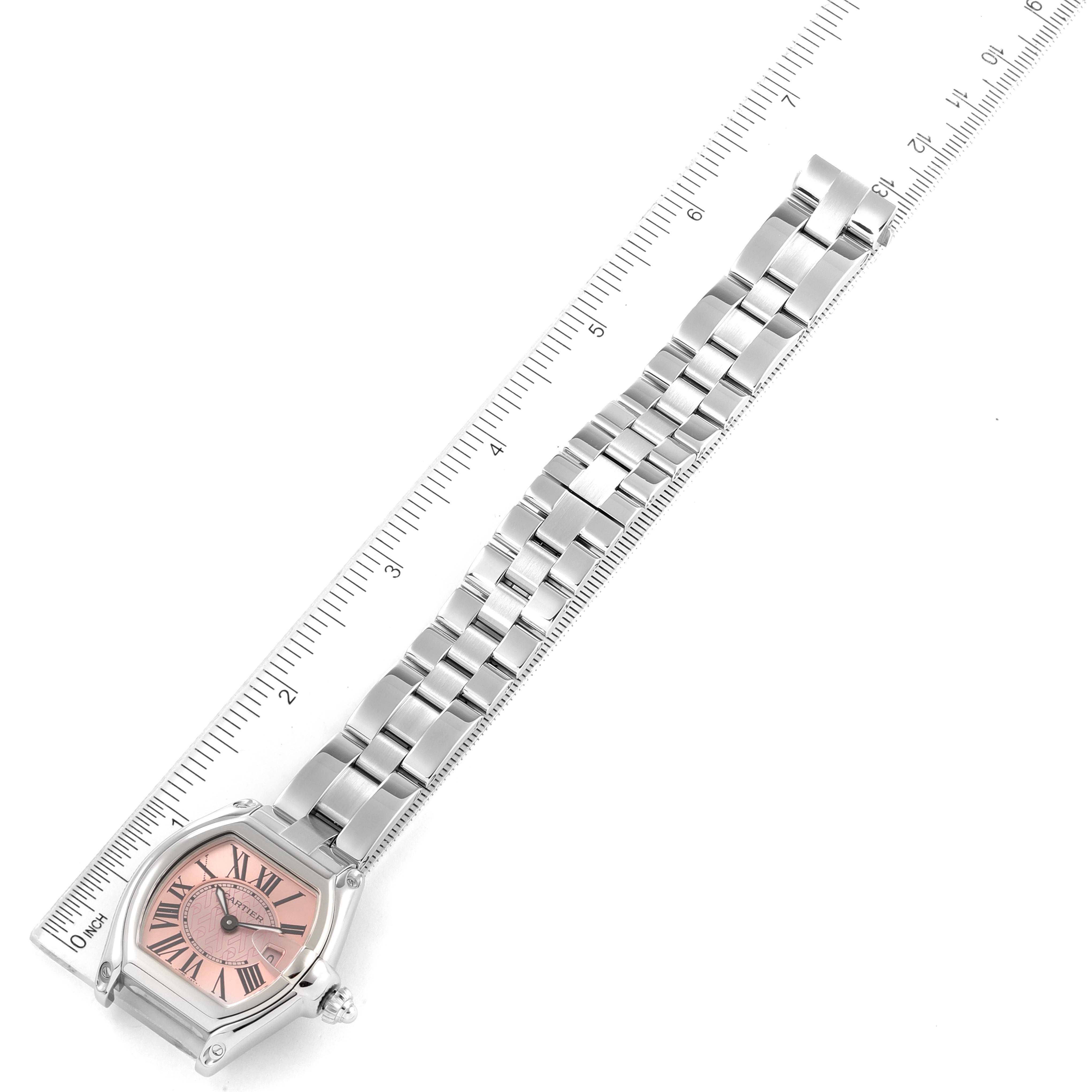 The Cartier Roadster W62043V3 Women's Stainless Steel Pink Dial W62043V3 Women's Stainless Steel Pink Dial model watch is shown from an overhead angle, displaying its face, bracelet, and clasp alongside a measuring ruler.