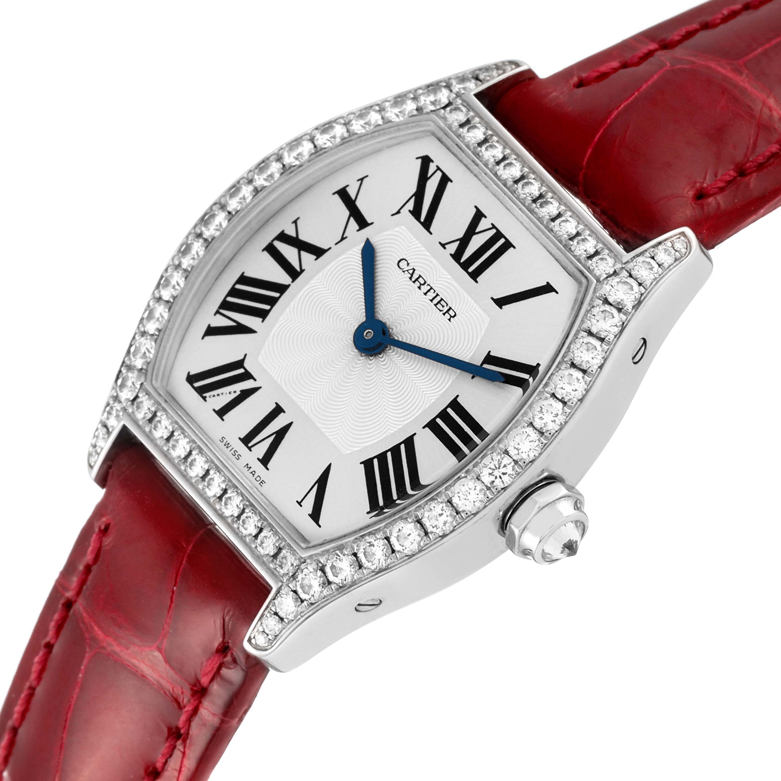 The Cartier Tortue WA501007 Women's White Gold Silver Dial watch is shown from an angled top view, highlighting its diamond-studded bezel, Roman numerals, and red leather strap.