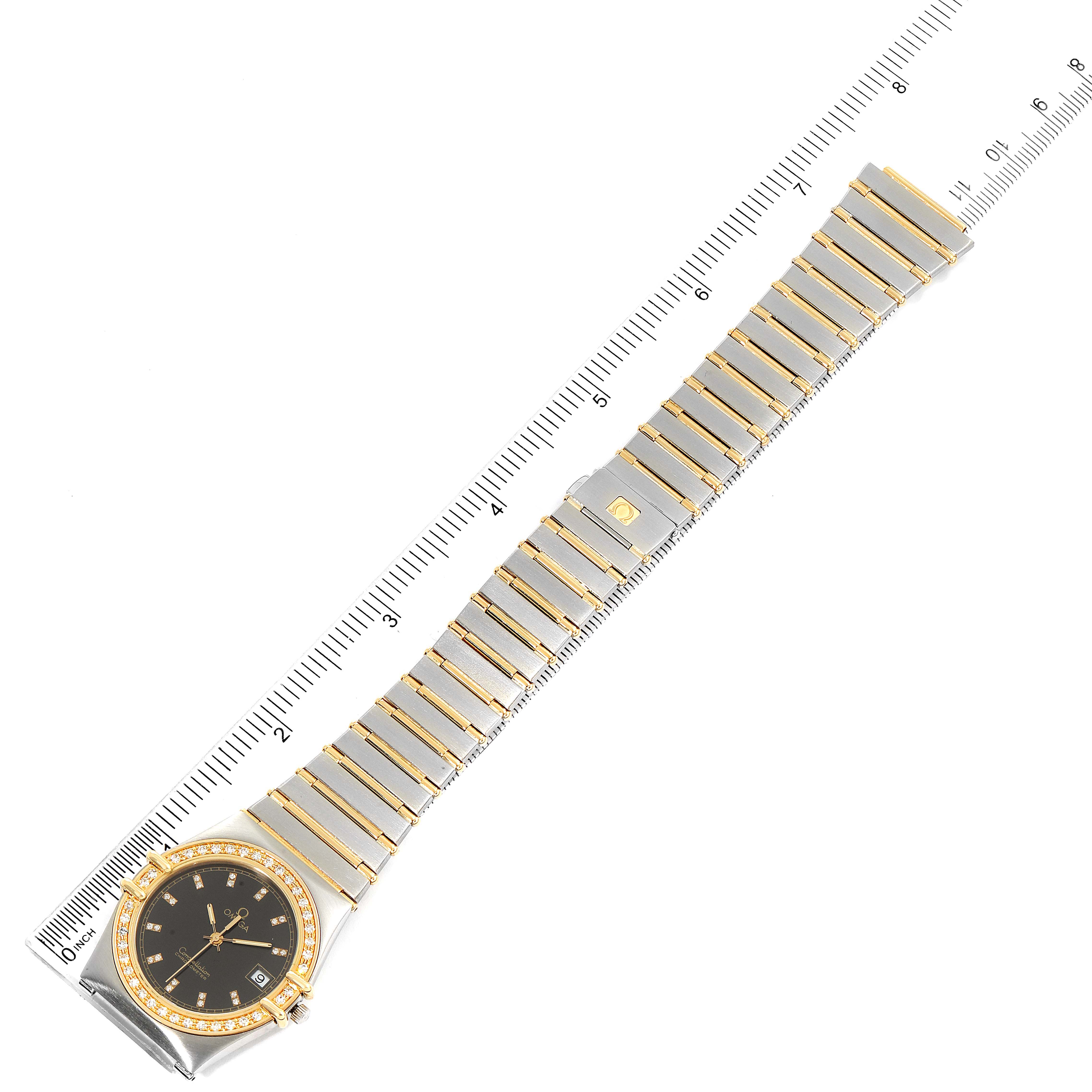 The image shows an Omega Constellation  Men's Steel and Gold (two tone) Black Dial  Men's Steel and Gold (two tone) Black Dial watch laid flat with its band extended, alongside a measuring ruler.