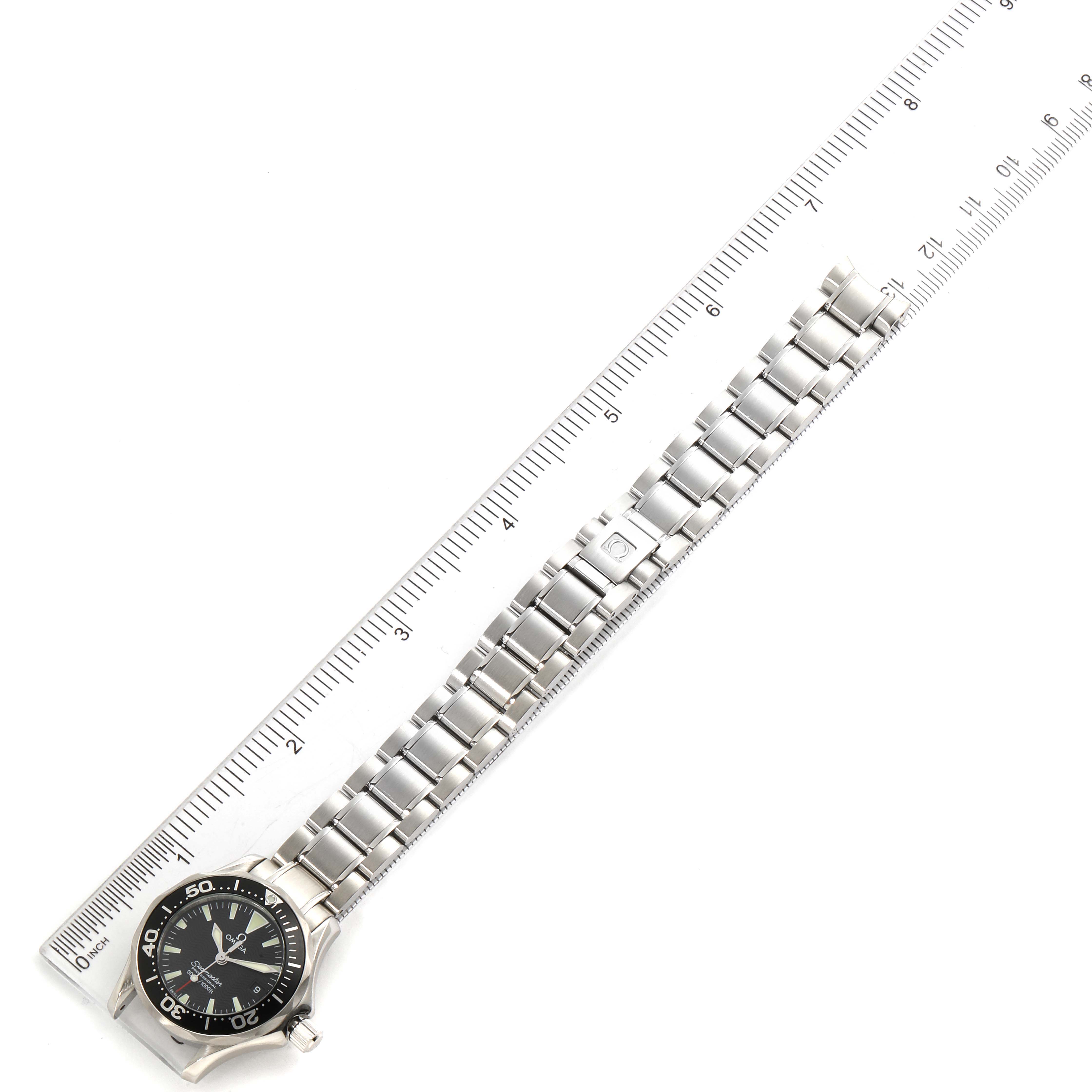 The image shows a top-down view of an Omega 2284.50.00 Women's Stainless Steel Black Dial 2284.50.00 Women's Stainless Steel Black Dial Seamaster Diver 300M 28mm Steel Ladies Watch model 2284.50.00 next to a ruler.