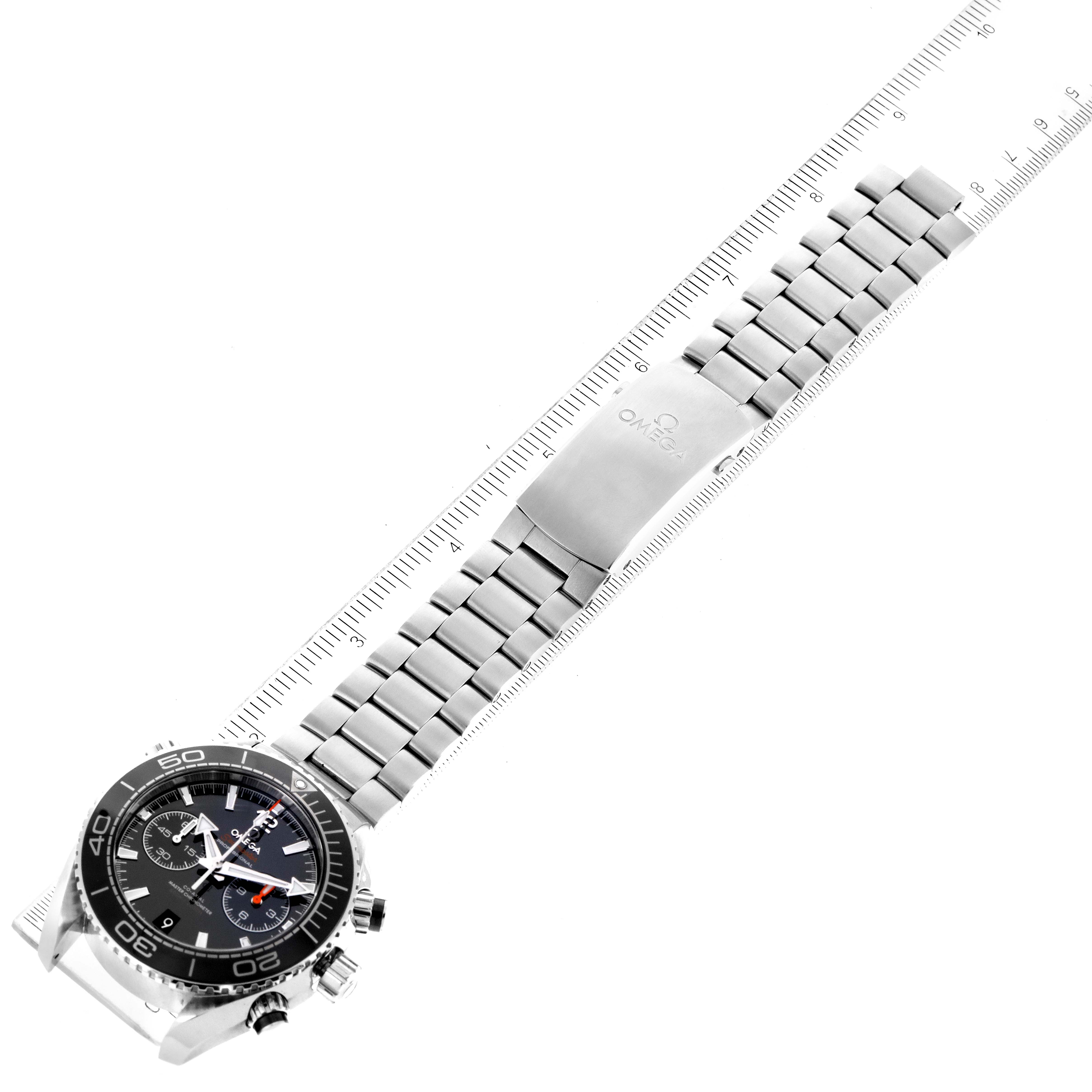 The image shows an Omega Planet Ocean 215.30.46.51.01.001 Men's Stainless Steel Black Dial 215.30.46.51.01.001 Men's Stainless Steel Black Dial watch laid flat, displaying the dial, bezel, and entire metal bracelet against a measuring ruler.