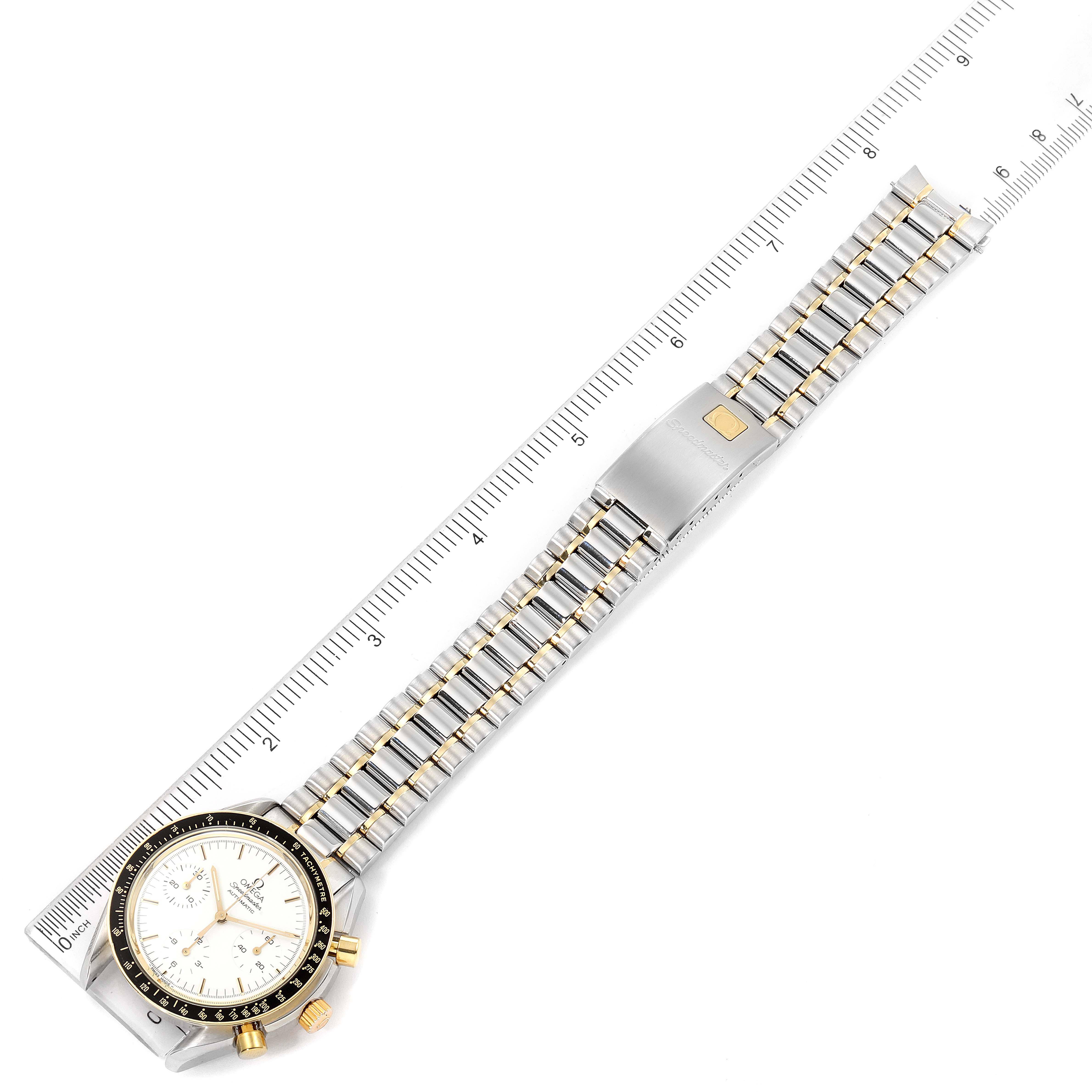 This image shows an Omega Speedmaster 3310.20.00 Men's Steel and Gold (two tone) White Dial 3310.20.00 Men's Steel and Gold (two tone) White Dial watch laid flat face-up with a ruler measuring the bracelet length.