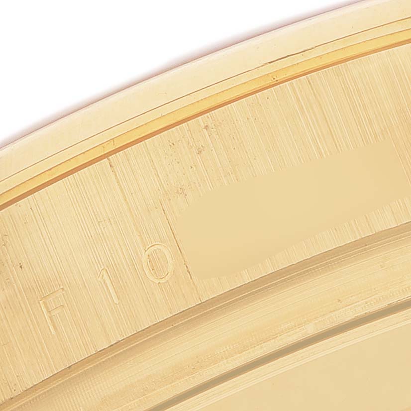 The image shows a close-up of the edge of the bezel from a Rolex Daytona 116528 Men's Yellow Gold Champagne Dial watch, highlighting its brushed gold texture.