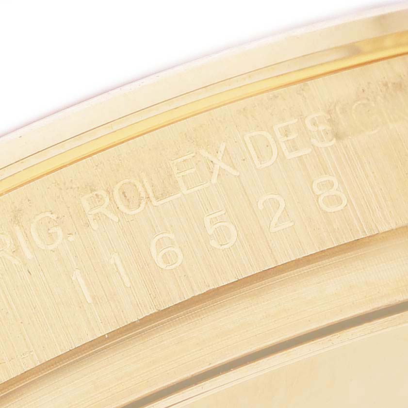 The image shows an angled close-up of the engraved bezel on a Rolex Daytona 116528 Men's Yellow Gold Champagne Dial watch.