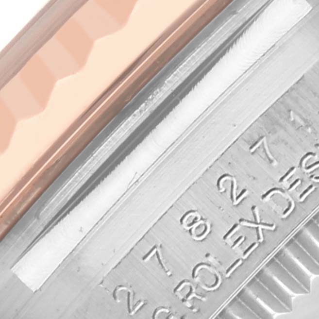 This image shows a close-up of the side of a Rolex Mid-Size 278271 Women's Steel and Gold (two tone) Grey Dial 278271 Women's Steel and Gold (two tone) Grey Dial watch, featuring the edge of the bezel and some engraved text.