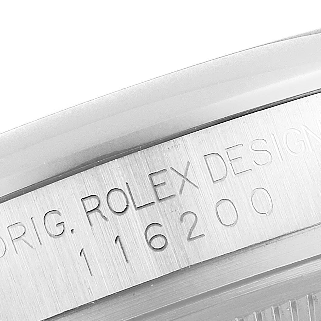 The image shows a close-up of the serial number and "ROLEX DESIGN" engraving on the side of a Rolex Datejust 116200 Men's Stainless Steel Blue Dial 116200 Men's Stainless Steel Blue Dial model watch case.